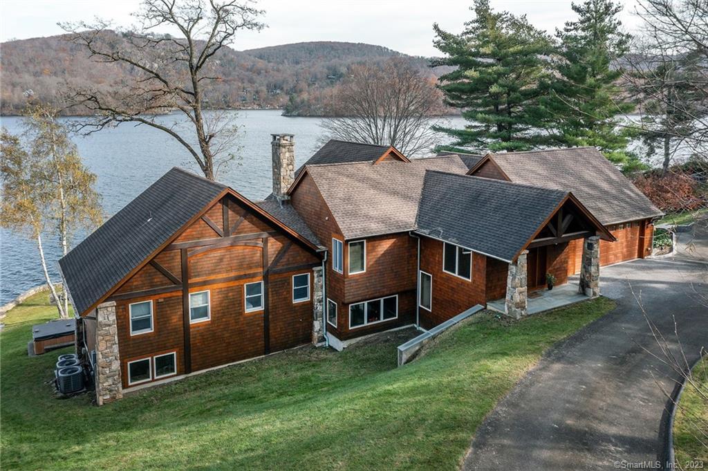 Exceptional Adirondack Waterfront, in the enclave of Sherman CT, showcases this 2012 built custom lake home with wide lake views, a lush lawn to the scenic & serene waterfront w/exquisite, panoramic lake views & near 200 ft frontage. A main level entry leads to the attached garage & 2nd floor bonus room ideal for office or bunk room. A turn stair leads to a great room plan with an expansive Chef's kitchen as the focal point. Large center island, breakfast bar & dining area surrounded by lake views. The adjacent family room and a second entertaining space/game room with wet bar & stone fireplace w/wood stove opens to a stone patio & expansive yard w/hot tub & fire pit; Ideal for outdoor barbecues, lawn games & lakeside fun. The main attraction is a 2 story, 30x18 screened porch w/stone floor & open lake views offering a cozy & protected spot for outdoor summer fun. Discover a private owner's retreat, with sitting area, WIC & custom stone bath. The private balcony views the lake & hills w a refreshing outdoor shower. Three more bedrooms & 2 full baths occupy a separate floor offering privacy for family & guests. Quality finishes, casual comfortable design & totally rebuilt in 2012. The perfect lake getaway but with full time amenities for full time enjoyment. Low taxes, no common charges & over 4048 SF of quality lake living(plus 500 SF screened porch).Two car attached garage, paved drive to accommodate 10+ cars, private dock & boat lift (opt)! Not to be missed!