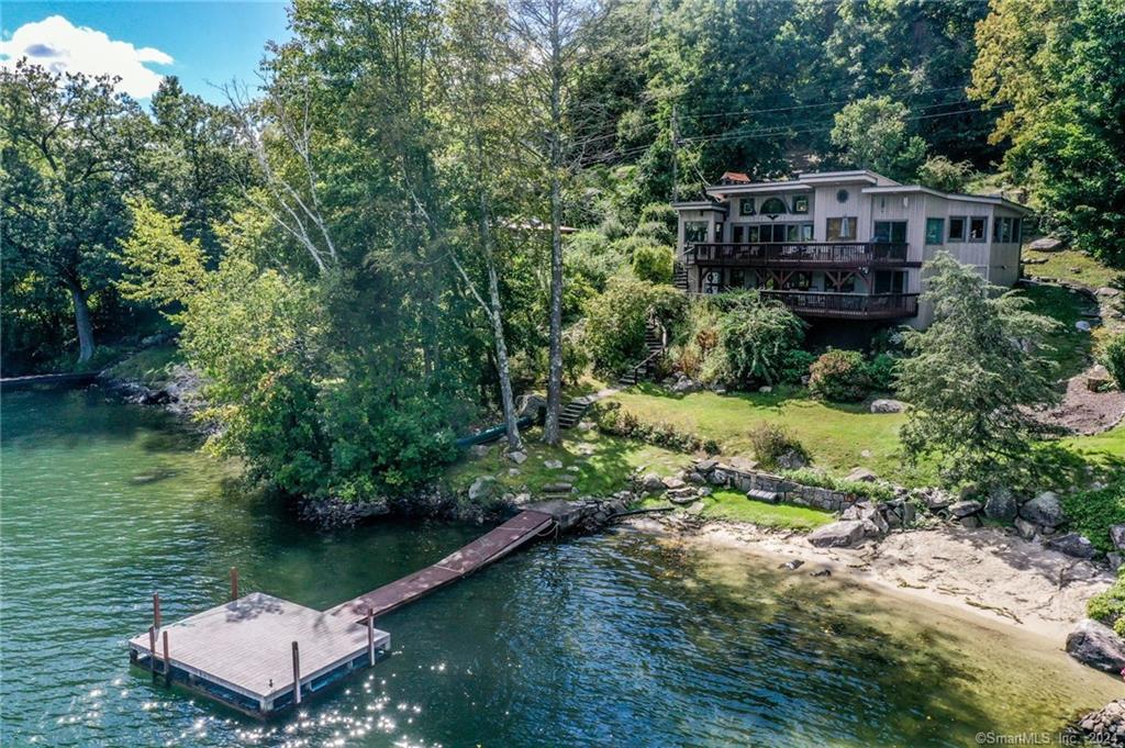 Feel right at home in this enchanting direct waterfront chalet! With views of the lake from nearly every room in the house, this is the perfect place to trade rush hour for happy hour . Attention to detail is evident in the quality woodwork that is showcased throughout. As soon as you enter the front door, you'll be impressed with the open floor plan that connects the updated galley kitchen with granite counters & a breakfast bar...to the living/dining room combination with its vaulted ceilings, stone fireplace, and walls of glass. Main level also includes a cozy den with exposed beams, a full bath, 2 bedrooms (one with a loft area!), and a sitting room that doubles as extra sleeping space. On the lower level you'll be impressed with the gorgeous wet bar/game room that has sliders to a paver patio, lakeside bedroom suite with full bath, and an office with built ins and sliders to the patio. This stunning home at the northern end of Candlewood Lake has a terraced walkway to its own private dock so you can enjoy a day on the water and an evening of relaxation. Its a perfect time to buy your waterfront dream!