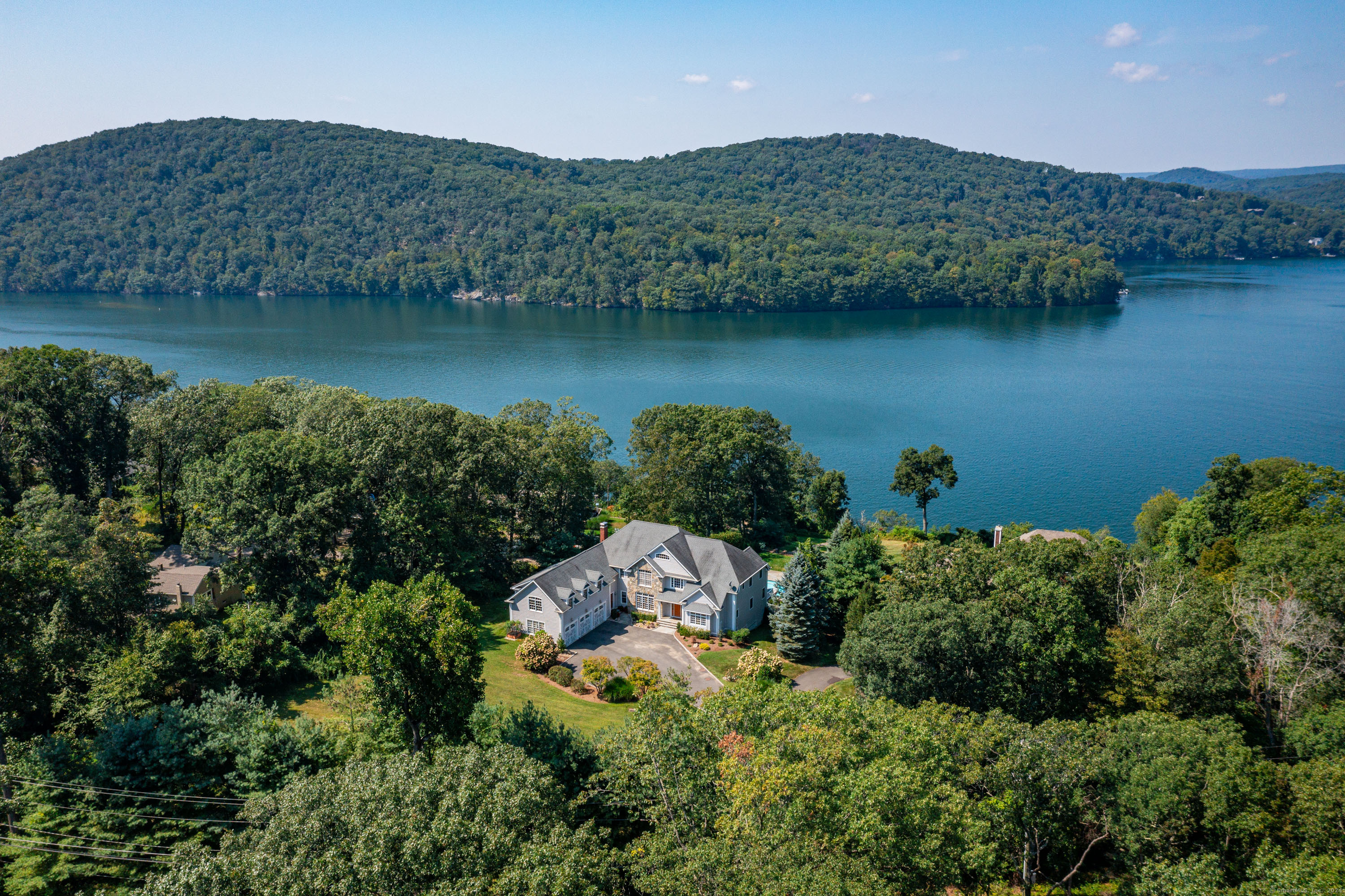 Candlewood Lake direct waterfront oasis complete with west exposure lake views, private boat dock, heated 20X40 in-ground gunite swimming pool with spa and outdoor cooking. The epitome of sophisticated elegance and casual lakefront living at its best! The spectacular views offer the most beautiful backdrop thru walls of windows and glass doors throughout the home. With over 8,900 sf of living space, this 4 bedroom, 4 full and 2 half bath home features an open concept floor plan on the main level, hardwood floors throughout, and plenty of space to entertain family and friends, both inside and out. Beautifully sited on 1.34 acres, the private setting includes breathtaking views of Candlewood Lake, professionally landscaped property, outdoor shower, stone walls and stairs to the private dock where you can enjoy the day at the lake sunbathing, boating, kayaking, paddle boarding, swimming and fishing. A few of the many benefits of this property: it is not a part of an association or tax district, there are no speed bumps, and it's minutes from all of Danbury's conveniences, yet you feel miles away from everything while enjoying lakefront living. Privacy, peace and tranquility abound at this west facing home with over 200+' of direct water frontage. The main level features a spacious two story entry foyer with hardwood floors and walnut inlay, a grand dining room with French doors, and formal living room with access to the deck. The gourmet kitchen has propane cooking, wall ovens
