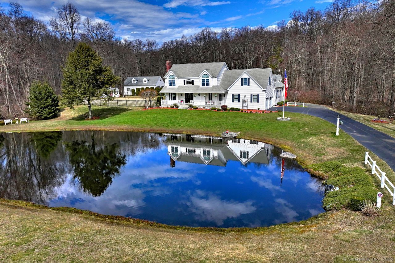 Welcome to 35 Candee Road. This stunning 2,799 square foot, three bedroom, two and a half bath home with a 1,100 square foot hard to find in-law apartment. Situated on 4.31 acres of meticulously landscaped property with a pond. Enjoy the peaceful setting and pond view from a large front deck. This stunning property boasts pristine hardwood floors throughout, a wood-burning fireplace in the main house and a gas fireplace in the apartment. Large eat-in kitchen with granit countertops and SS appliances. Dining room with sliders to screened-in porch make entertaining a breeze. All bedrooms have walk-in closets, the primary bedroom has vaulted ceilings and a Whirlpool tub. The first floor has great space off the kitchen for a nursery or office with a closet. The upper level can be accessed by one of two separate staircases. Upon arriving on the second floor you will be greeted with an abundance of natural light. There is an entrance to an oversized bonus room for a host of entertaining possibilities.  The separate in-law apartment has vaulted ceilings, eat-in kitchen , pocket doors for wider entrance if needed and private entrance and its own deck. Now lets go outside! The Paver patio with pergola and grill with gas hook-up make it the perfect place for those outdoor gatherings. Fenced-in tree-lined yard with two sheds perfect for safety to play and pets. If so desired there is room for a pool. This home has enough acreage to have horses if so desired.