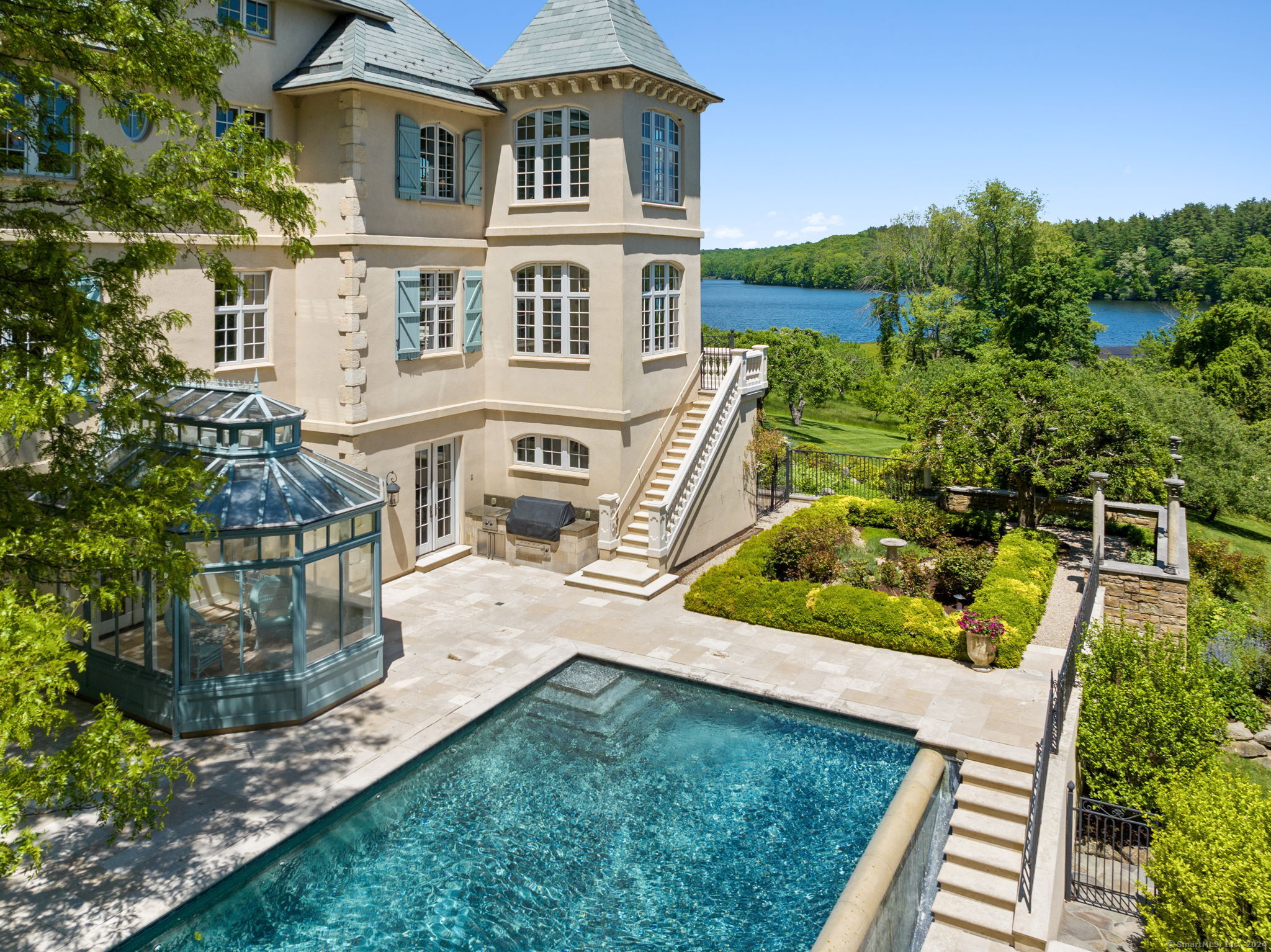 Be transported to Europe, without leaving the country! Experience breathtaking water views from this extraordinary estate nestled on 2.29 acres in South Wilton. Embracing European elegance, this coveted Nod Hill residence exudes luxury & meticulous craftsmanship from its slate roof down to its pool-side solarium. With soaring ceilings, limestone fireplaces, custom millwork & the finest materials imported from France & Italy, every detail reflects unparalleled quality that would be hard to duplicate today. Spanning 4 finished floors, this home offers space for all to enjoy–from quiet, cozy gatherings to grand parties. Entertain with ease! The light filled interior seamlessly blends modern comfort w/timeless elegance. The chef’s kitchen features top of the line appliances, pantry, fireplace, dining area & French doors opening to the terrace. The 2-story family room/library w/stunning fireplace offers a cozy space to enjoy quiet time w/a book or media. The primary suite provides a private oasis w/sitting room, luxe ensuite bath & fireplace. The piece de resistance is the stunning property…terraces overlooking Streets Pond, patios by the infinity edge pool, atrium, manicured gardens w/fruit trees & sweeping lawn. The pool “house” w/kitchenette, full bath & space to lounge, is perfect for hosting summer gatherings. With the allure of water views & gracious sophistication, this home offers a sublime lifestyle. Don’t miss the opportunity to own this exceptional piece of paradise.