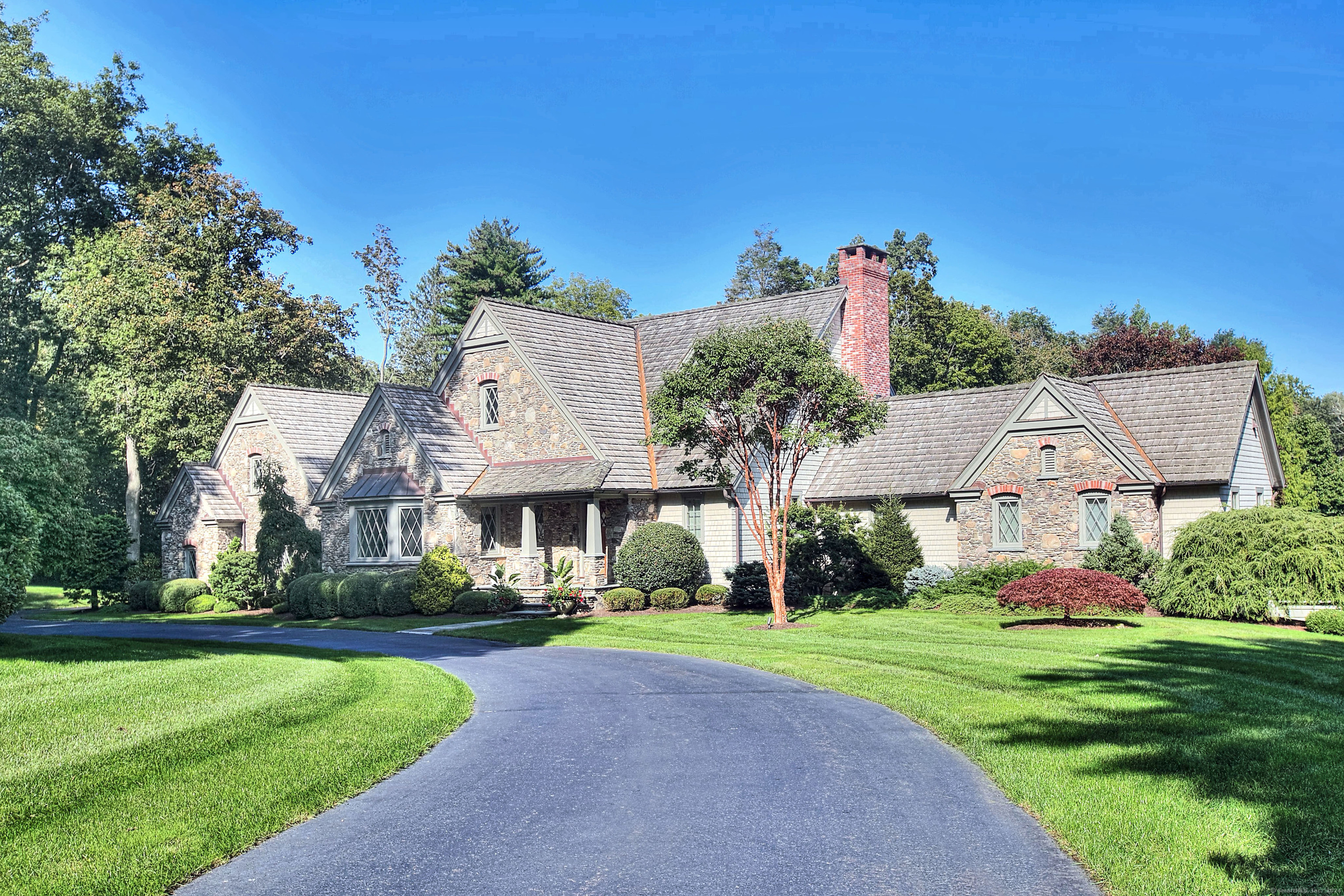 This distinctive estate in Lower Greenfield Hill offers the ideal blend of Old World style and character with the benefits of high-quality, recent construction. Set on over two acres of exquisite grounds with rich history and provenance, this is a rare find that will enchant you upon arrival. The stone and shingle design of this residence speaks to the quality and timeliness of the interiors that await your discovery. The open floor plan lends itself to effortless entertaining, while stone fireplaces, custom beams and tasteful millwork infuse a sense of history and warmth to the gracious spaces. Distinctive features include the custom gourmet kitchen with Wolf, Miele and Sub Zero appliances, artisanal cabinetry, a butler's pantry and great flow into the family room with an incredible fireplace and cathedral ceiling. The first floor primary suite is a luxurious retreat, complete with a fireplace, elegant private bath and an expansive custom closet. The flexible layout includes spaces for fantastic home office space, in-law suite, staff quarters and much more. Auto enthusiasts will want to take note: this property offers both a three-car attached garage, as well as an incredible five-car heated carriage house offering a total of eight garage bays. The postcard-worthy acreage includes a pool and sunken garden, featured in prestigious garden tours. Imagine an incredibly tranquil retreat that offers direct convenience to town, commuting, and all amenities.