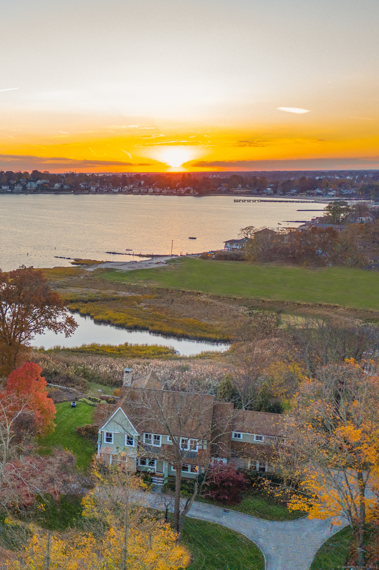 Savor sunsets across Westcott Cove and LI Sound every day from this superb Wallacks Point property. The mesmerizing unobstructed views from this impressive newer colonial are trimmed with perennial gardens and stone walls, and buffered by protected conservation land. Built by in 2007 with forward-thinking design by the architect, Neil Hauck. The interior embraces spectacular South and Westerly views on all three floors. A wide first floor entry is flanked by a light-filled living room and library, and extends through to a beautiful open-plan great room complete with gourmet kitchen, dining area, and family room with stone fireplace, all opening through French doors to a wide deck and covered porch, and large terrace beyond. A well-outfitted pass-through butlers pantry and separate