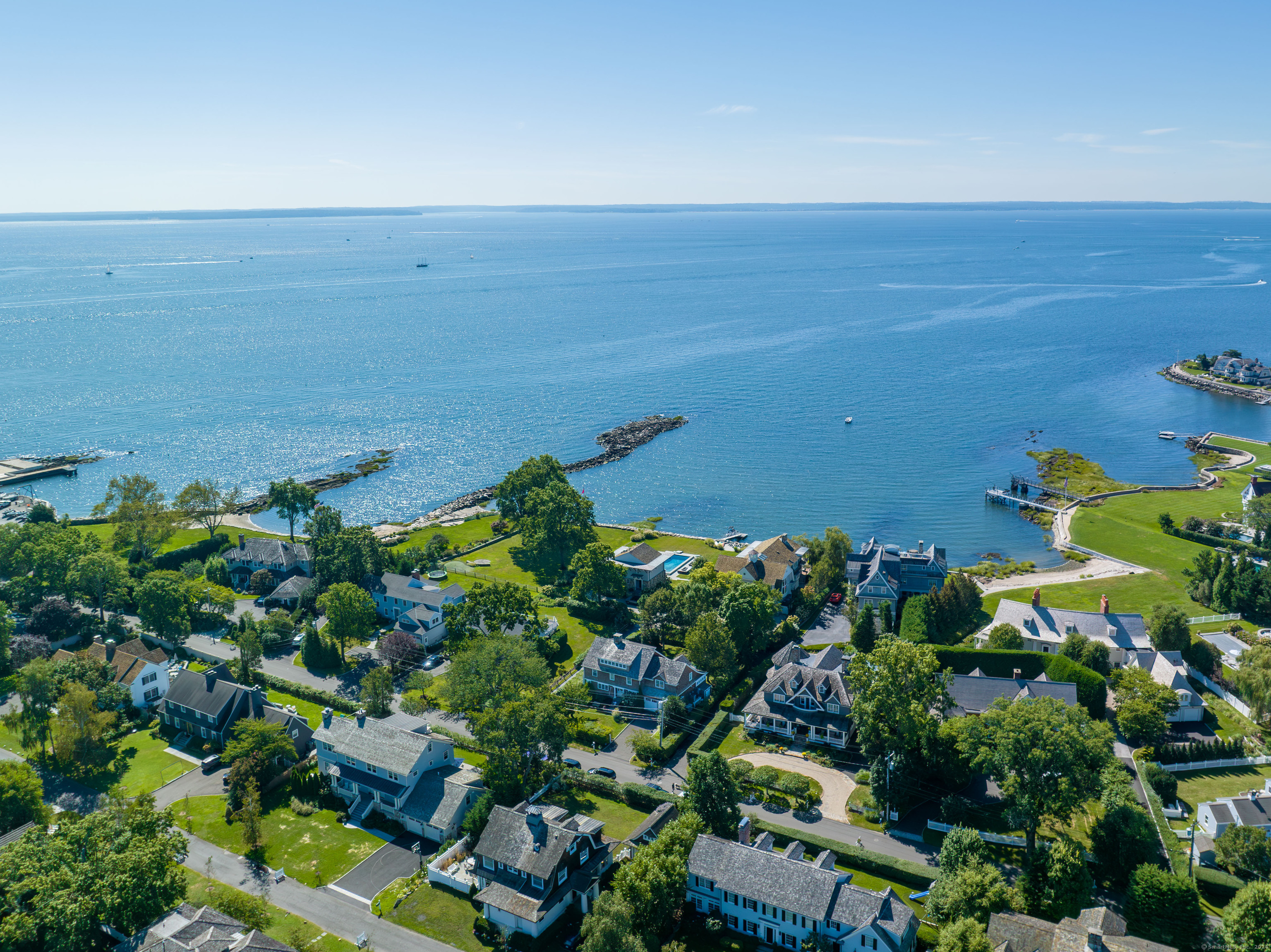 Explore the serene beauty of coastal living in this beautifully crafted New England home situated in the heart of Old Greenwich's waterfront district, close to shops and restaurants in the village. This residence offers a unique blend of traditional architecture and modern comfort, strategically designed to capture sweeping views of Long Island Sound. Each room is thoughtfully oriented to maximize exposure to the tranquil waters, ensuring a constant connection to the natural surroundings and filling the home with a peaceful, airy ambiance. Experience refined elegance in this impeccably updated traditional home, seamlessly blending contemporary features with the timeless charm of a shore colonial.  Enjoy expansive water views from nearly every room of this spacious three-story home, which spans more than 4,300 square feet. The kitchen, a showcase of modern efficiency, offers extensive counter space and ample storage, complete with a quaint dining area that makes every meal a delight. The spacious Great Room, brightened by a large bay window, offers stunning water views. French doors lead to a generous south-facing deck, perfect for outdoor gatherings and relaxation. Accessible from both the Great Room and the adjacent family room, the deck enhances the home's connection with its beautiful waterfront setting. A well apportioned office complete and spacious powder room complete the main level.