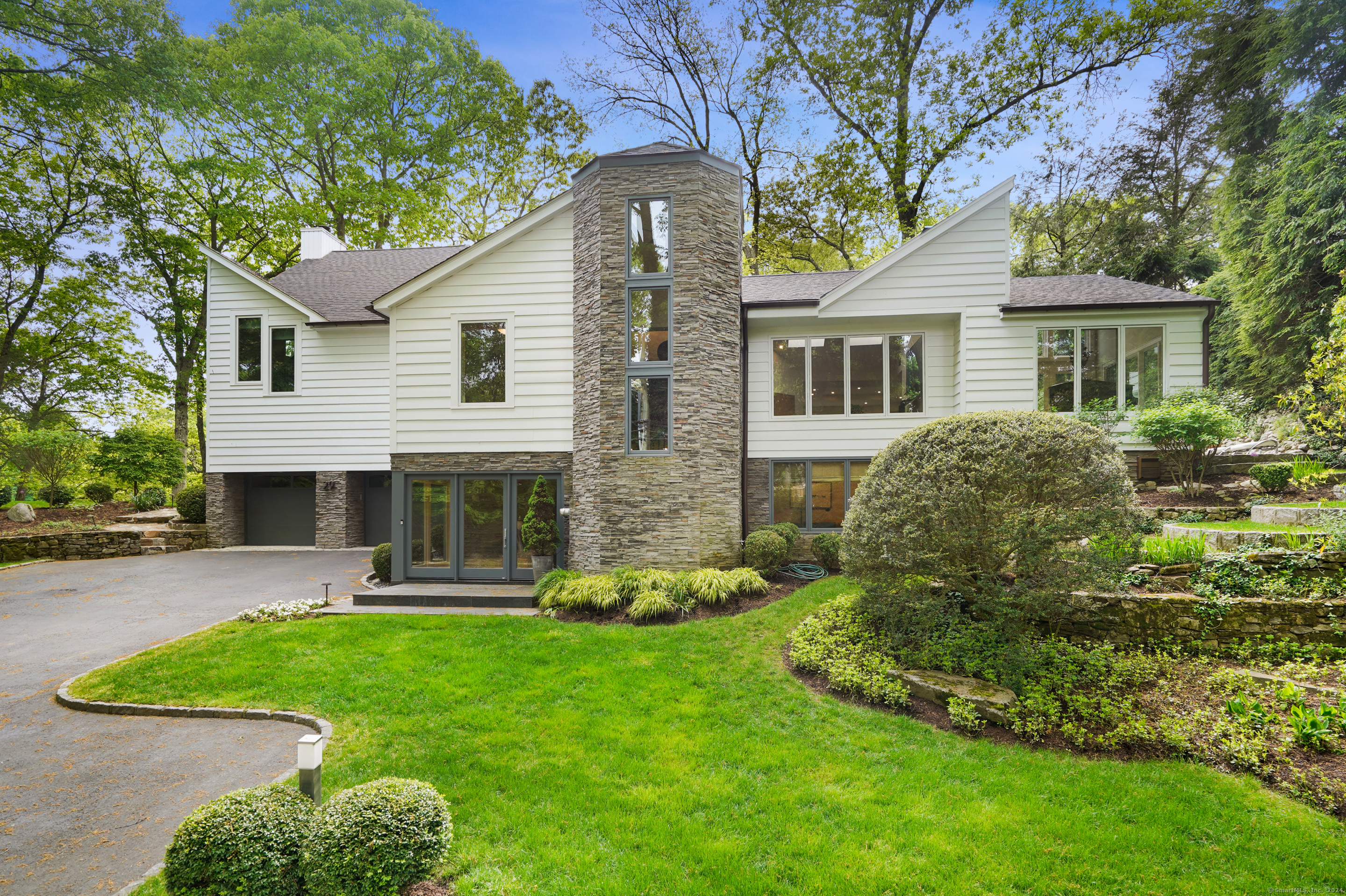 This classic modern home boasts architect-designed features, including custom fireplaces and European high-end fixtures. Its meticulous attention to detail and luxurious finishes are evident throughout the property. Situated in a park-like setting, overlooking a tidal pond it offers the convenience of being within walking distance to downtown Westport, Compo Beach and Metro North.The glass & stone foyer leads directly up to the main floor, where soaring ceilings, and the warm, welcoming fireplace work together with the oversized windows and skylights to create a spectacular central living room.The kitchen is spacious and top notch, with custom cabinetry, high end appliances, a large island and a lovely dining area overlooking the water. There is a formal dining room and a gorgeous music room/den with a fireplace that both exit to a stone patio area on the side of the home. In the bedroom wing, there are 2 generously sized bedrooms that share a hall bath and the primary suite. The 1st floor of the primary suite consists of the main bedroom with a wall of windows towards the pond, a stylish marble bath with soaking tub, and custom fixtures, and a large walk in closet. The suite continues to a 2nd level where there is vaulted ceiling sitting room/office with fireplace and deck, a nook currently being used as a home gym, and a half bath. The lower level is anchored by a large recreation room, complete with a wine cellar! The 4th bedroom & full bath are privately placed on the LL.
