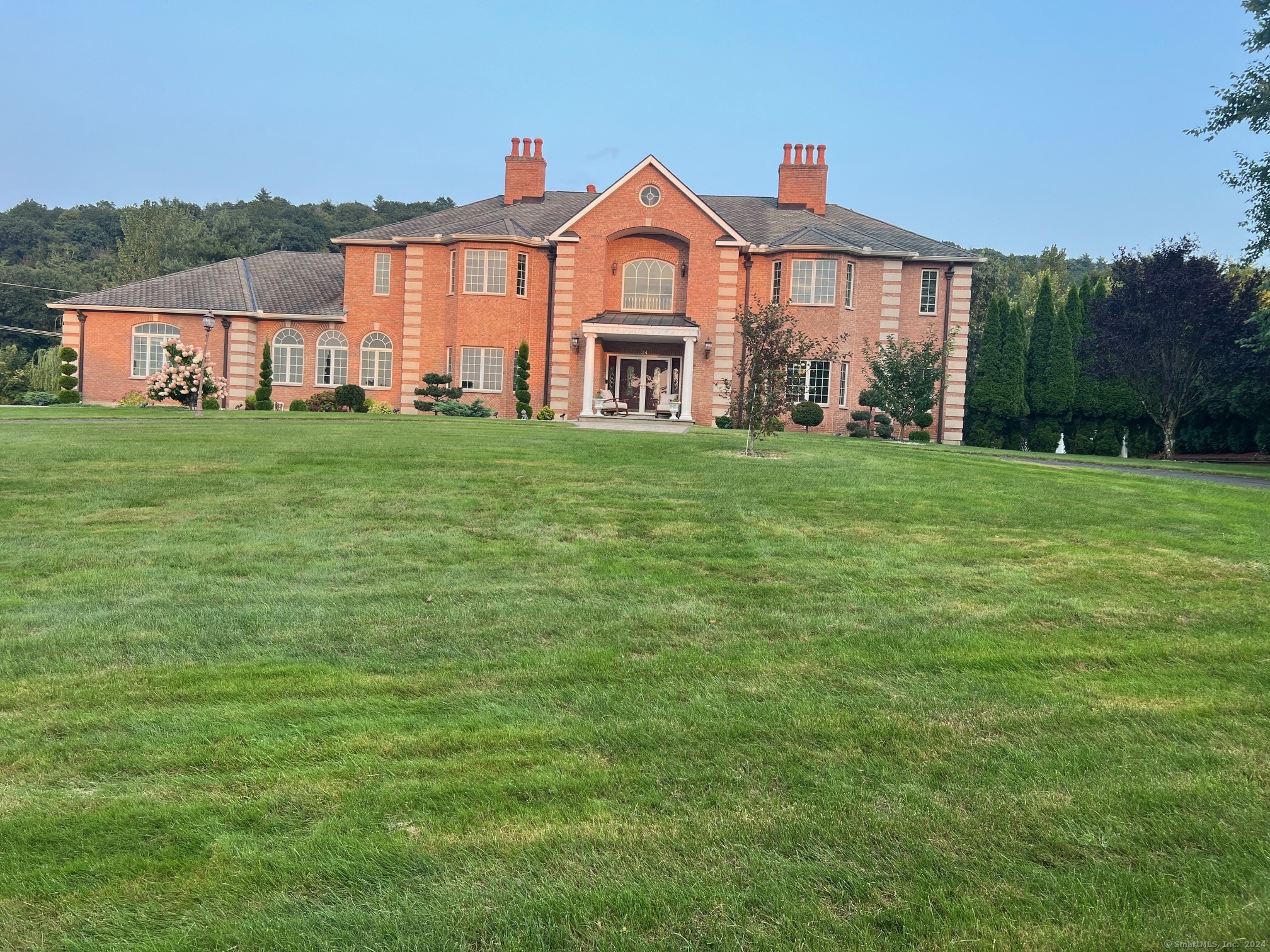 This stunning brick Colonial sits atop Hunting Ridge Drive on a sprawling two-acre level yard, offering far-reaching views across the Farmington Valley and spectacular sunsets! The back of the property also boasts amazing Mountain View's with access to a hiking trail. Immerse yourself in nature's beauty at the nearby Flower Bridge, with the Farmington River just a few blocks away, offering endless opportunities for outdoor adventure. As you enter the marble, two-story foyer, you will be captivated by the craftsmanship and attention to detail. This home features a spacious chef's kitchen of approximately 1, 000 sq ft, complete with ample cabinetry, abundant lighting, a fireplace, a large island, an informal dining room. The kitchen is equipped with two wall microwaves, two wall ovens, two dishwashers, 3 sinks and two additional mini-fridges. It also has a formal dining room with a tray celling and 3 large windows to see the breathtaking views. The first-floor master suite includes a Brazilian cherry wood office/library, while the second-floor master suite comes with its own study/office room. Additional features include seven exquisite fireplaces, 10-foot ceilings on the first floor, a circular driveway, a large trex deck, a flat backyard, and a finished lower-level recreation room. Simsbury was recently ranked as one of the Best Small Towns in Which to Live by Money Magazine, with its many cultural events, top-rated school system, and preserved open spaces. **EXQUISITE*