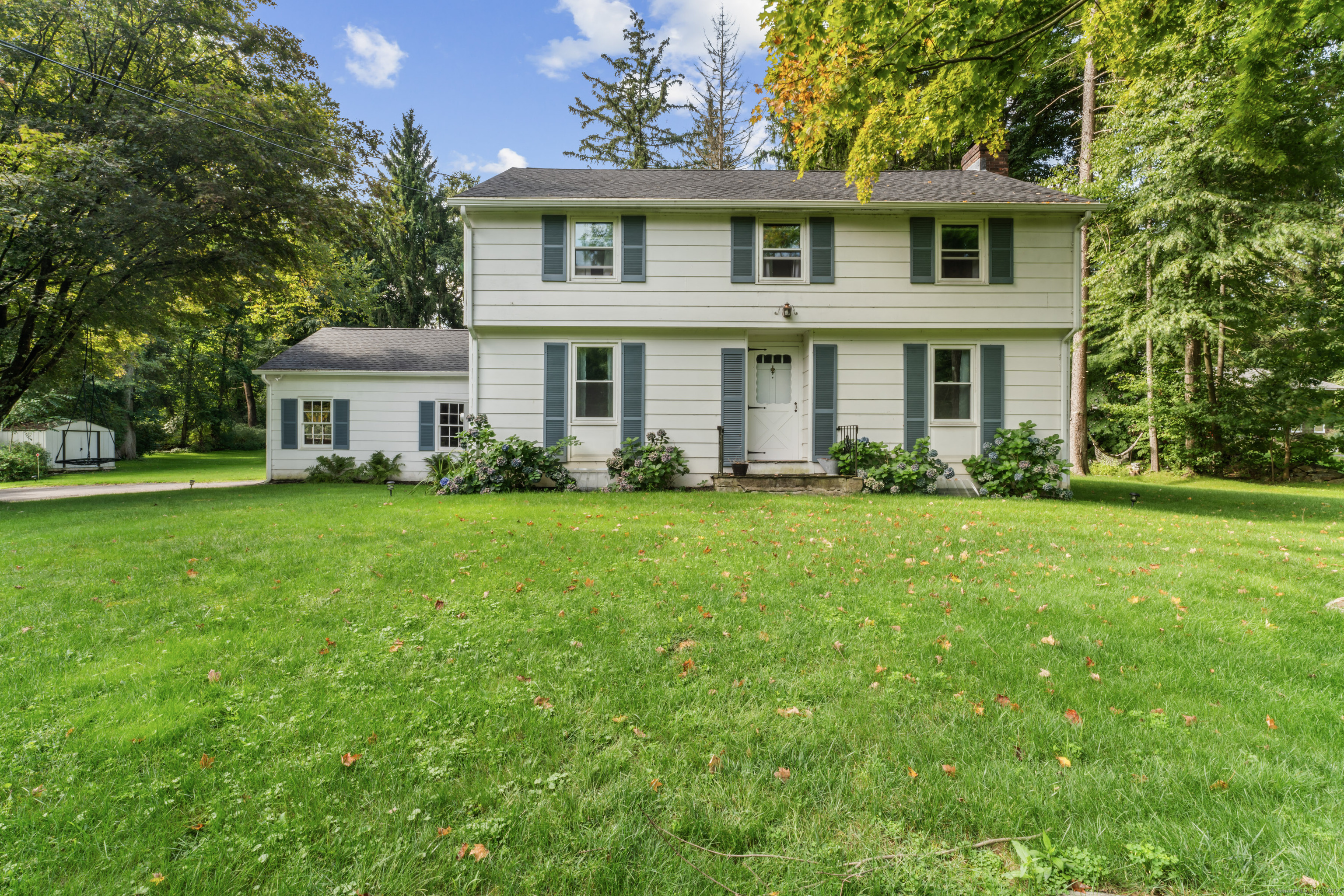 This 3-bedroom, 1.5-bath Colonial in Newtown presents a blend of charm and modern updates. Situated on a flat acre of land in Fairfield County, it's conveniently located near major routes like Rte 6, Rte 25, and I-84. Recent renovations include paint to walls, doors and trim, new vinyl replacement windows (2022), new roof with gutters and leaf guards (2023). The home also features two newly updated bathrooms (half bath 2018 and full bath 2022), a refaced fireplace (2022), and beautifully refinished hardwood floors. The main level boasts a spacious family room with a fireplace and a 48-pane window overlooking the level backyard. The kitchen is clean and functional with stainless appliances and new backsplash. A cozy dining area allows for entertaining in class. Off the kitchen walk out to newer pressure treated deck (2020). Upstairs, you'll find three generous bedrooms with hardwood floors throughout, a full bath, and laundry room with shelving. The basement comes with ample space for customization, and comes with well maintained Weil-McLain Gold Furnace and heavy-duty Roth stainless steel oil tank. The property includes a breezeway leading to a 2-car garage with high ceilings, ideal for storage or projects. The house is set back from the road, offering a serene, park-like backyard. It's a must see.