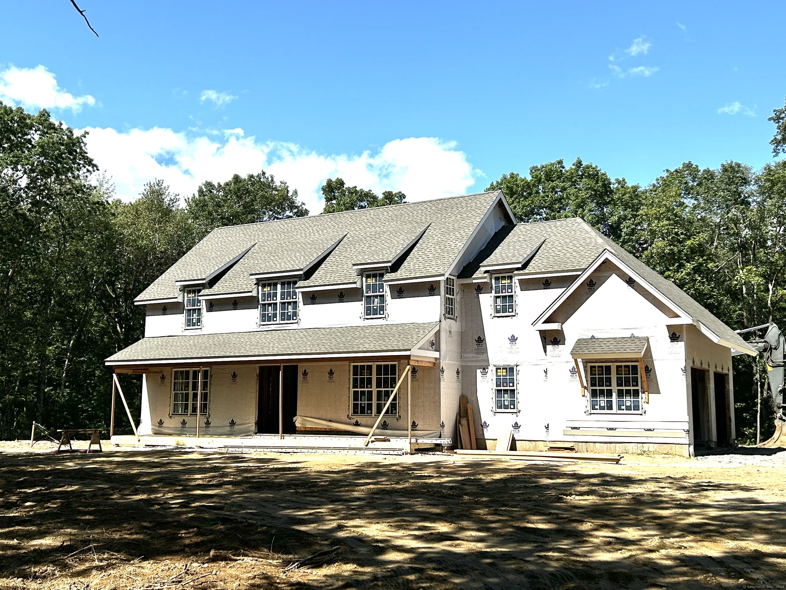 This new construction home is located in the desirable St. John's Peak neighborhood of Kent. The wooded property of 12 +acres and with 700 ft of frontage on Stonewall Lane affording great privacy. The level home site creates a very useable yard with ample space for a future pool. The home's exterior, with its shed-roof dormers and full-width porch, evokes an English country home. This style continues to the interior with rooms that have alcoves, sloped ceilings, exposed wood beams, and random pattern 3-5-7 flooring. With lots of windows, first floor ceilings that are 10' and second floor ceilings that are 9', the interior has an open and airy feel. From the 2 car garage you enter into a large mudroom with storage space that includes a coat closet, pantry, and bench seating. From here, you step into the spacious custom-crafted kitchen that opens to the outdoor patio and backyard with 9 ' sliding doors. The kitchen opens to a dining space with large windows as well as the family room with a stone fireplace and built-ins. Rounding out the first floor is a very comfortable office/den, also with numerous cabinets and built-in shelving. The primary bedroom and 3 additional bedrooms are located on the second floor along with 3 full baths, a laundry room, and a loft area with built-ins. This home comes with a one year Builder's Warranty. The siding is in progress with sheetrock in place on the interior. Interior trim starting mid-October but still plenty of time to customize.