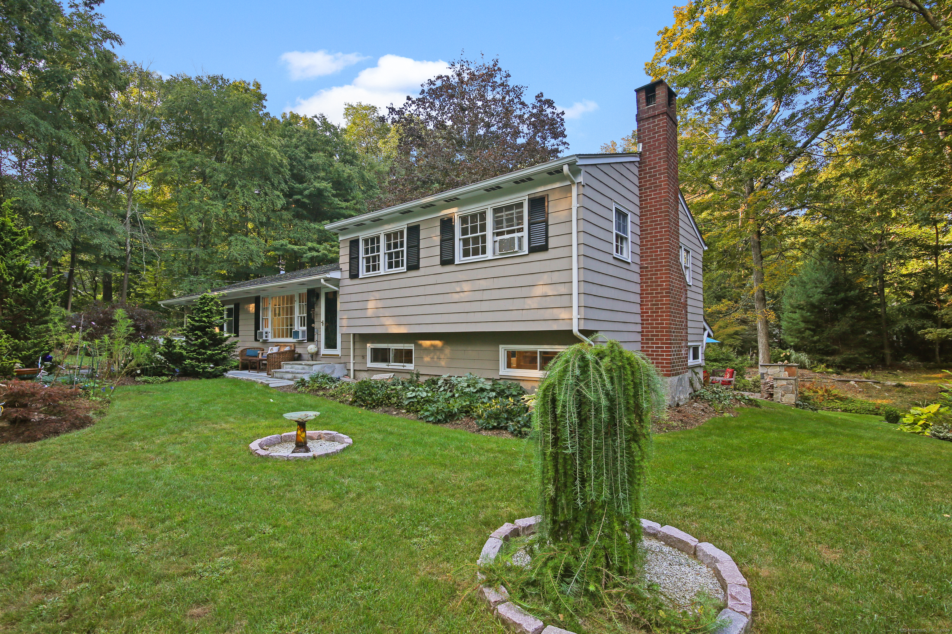 Welcome to this pristine, well-maintained 3-bedroom Split-Level home, nestled on a beautifully landscaped lot in a peaceful North Ridgefield neighborhood. As you step inside, you're greeted by a light-filled living room with large windows that bathe the space in natural light. The updated eat-in kitchen, with convenient access to the 2-car garage, with ample cabinetry, a central island, and sliding glass doors that lead to the backyard. This design invites sunlight in while providing a seamless connection to the outdoors. The split-level layout creates a unique and practical flow, with the living and entertaining areas on one level, while the bedrooms are thoughtfully tucked away on another, offering both openness and privacy. The spacious lower-level family room features a wood-burning fireplace, perfect for cozy winter evenings, and a walk-out to the backyard oasis. Outside, the professionally landscaped yard is a true retreat, featuring lush greenery, vibrant flower beds, water features and a charming deck and patio with a stone fireplace-ideal for relaxation or outdoor dining. With its sun-filled interior and stunning outdoor space, this home brings the perfect balance of comfort and tranquility.