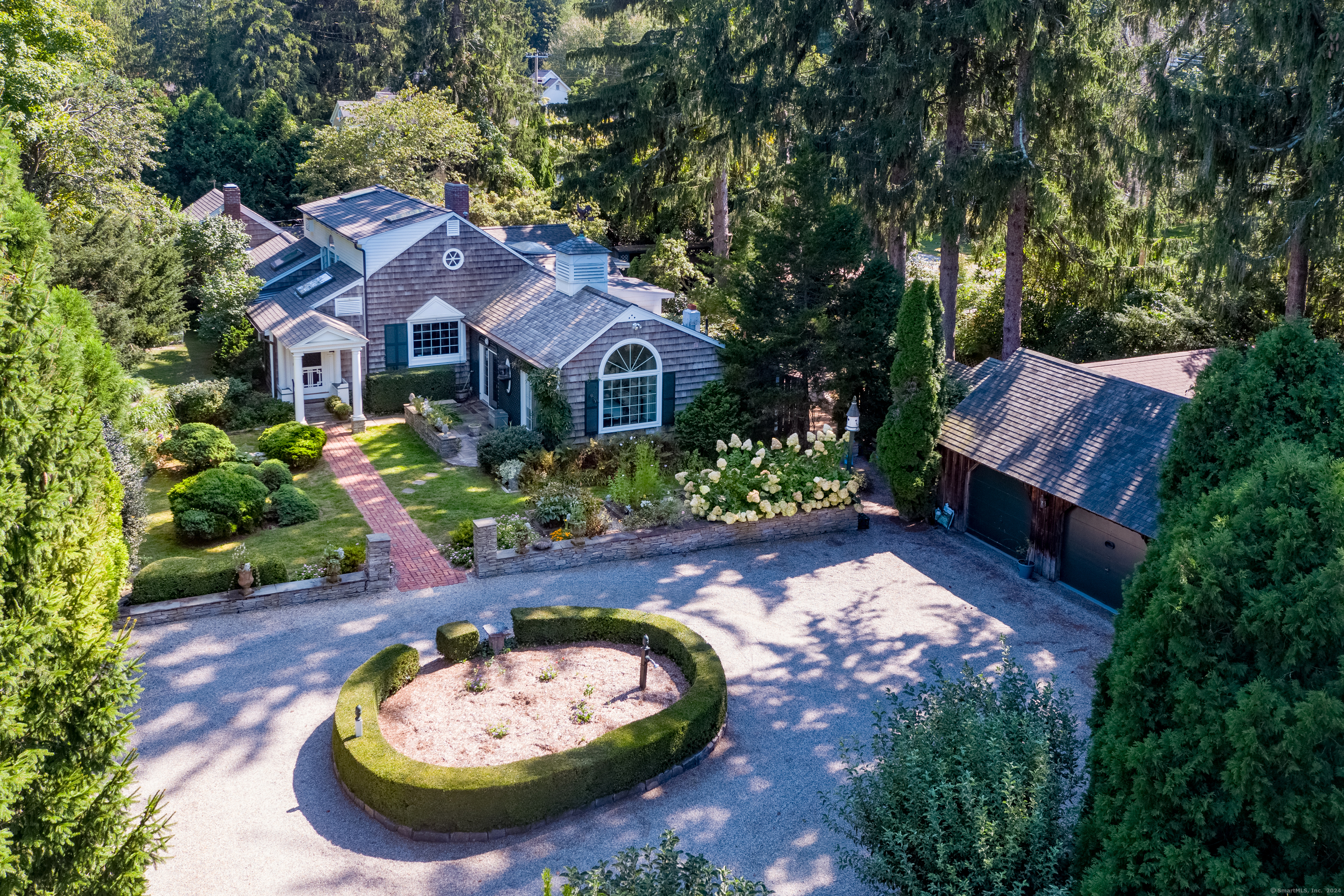 Wow! sums it up. As soon as you enter the graceful landscaped grounds through the circular crushed stone drive, you know you are in enchanted territory. Built in 1950 and refined over the years as an artist's retreat, this shingled home defies labels. It is fanciful, yet grounded by features such as a first floor bedroom suite, living room with parquet flooring and fireplace, a chef's kitchen with walk-in pantry, and cozy den with bookcases. The breakfast room is flooded by light. A corn crib addition with fireplace and soaring exposed beam ceiling, anchors the far end of a dramatic vaulted entry foyer filled with bookcases and wall space galore to feature art and treasures. A spacious bedroom suite with renovated full bath, including double sinks, marble countertop, heated flooring, and shower is found on the upper level. The terrace outside the kitchen provides a marvelous al fresco dining experience by the fish pond. It's not hard to envision you are dining in Provence or Tuscany. The outbuildings, gardens and frog pond add more layers of utility and panache to an already otherworldly tableau. The outbuilding closest to the main house provides a half bath, making this space suitable as an office, studio, or for use as a guest bedroom. Another office is attached to the cavernous heated and air conditioned garage. Additional outbuildings provide storage and studio space, and a detached one-car garage. Deeded water access. Come for a tour and fall under the spell!