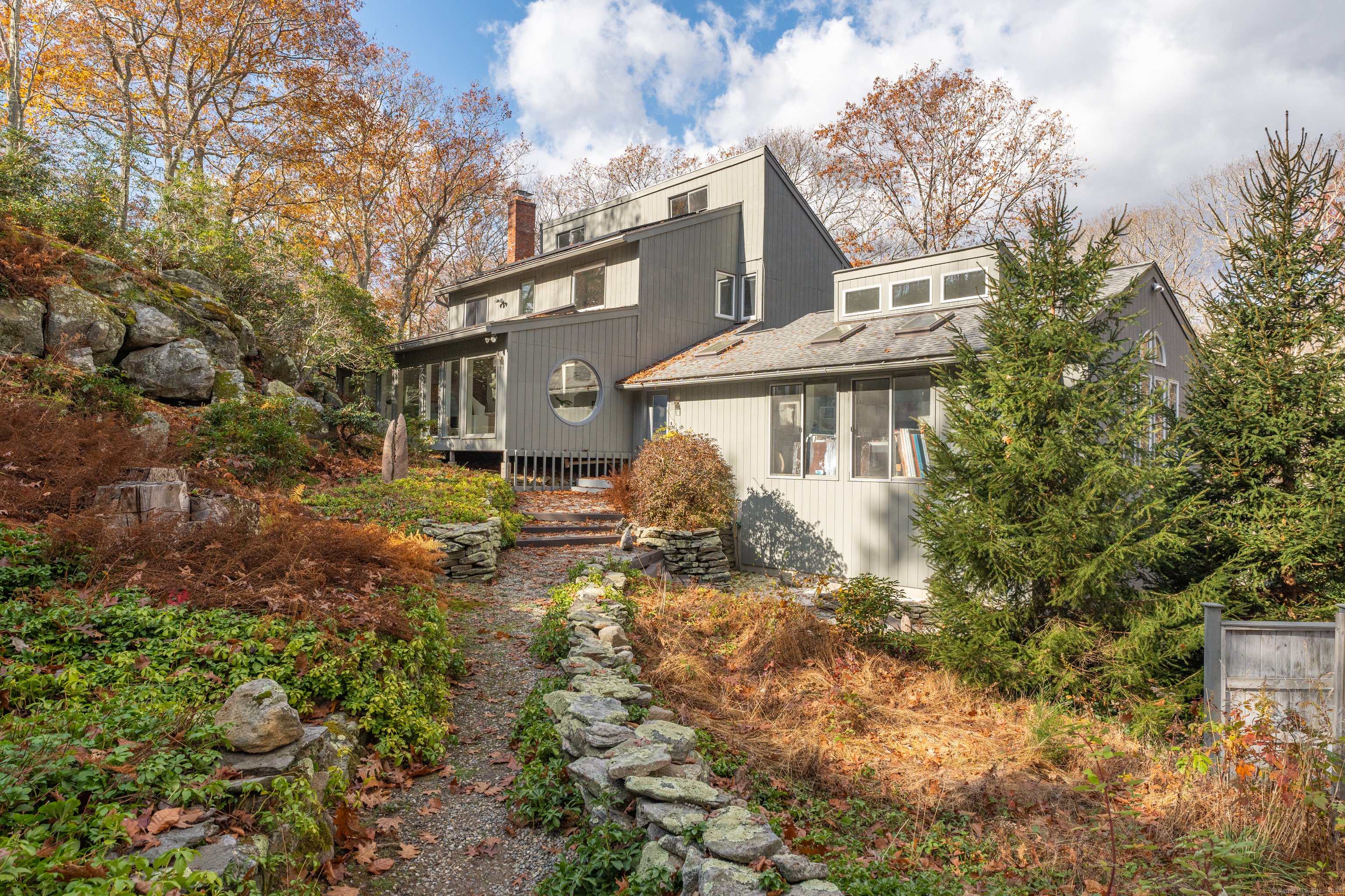 DRAMA and SOPHISTICATION. This Contemporary Home, built in 1973, has been expanded and beautifully enhanced to create a strikingly dramatic home. the rooms on the main floor, while individually distinctive, flow from one to the next with ease. The Solarium, at the back of the house is particularly impactful with walls of floor-to-ceiling glass, five skylights, and views of the landscaped granite rock out-cropping. The Kitchen has been completely remodeled with up-to-date materials, appliances, and center island. A special feature of the home is the large studio that has windows on three sides. The space is now a real workspace and could easily become a finished Bonus room or main floor Primary Suite with lux bath and walk-in closets. The lower level has many built-in shelves and storage and has one of the two fireplaces. The other fireplace is in the living room. The top floor has three bedrooms including the Primary bedroom with ensuite bath, double closets and a Juliette balcony accessed by siders. The upstairs hall overlooks the dining room. Outside there is an extensive deck that is well screened from the road by plentiful, mature plantings. There is a storage shed and a play/tree house on the property plus a whole house Generac generator.