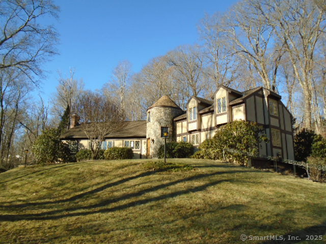 Experience the charm of this exquisite French Normandy chateau, set on 2.69 private acres in a serene natural environment. This stunning home boasts a striking center stone turret and a welcoming foyer with a beautiful spiral staircase and tiled floors. The spacious open living room features an oversized marble surround fireplace, a soaring vaulted ceiling, and an interior balcony that adds a touch of elegance. Enjoy formal dining in the elegant dining room, which conveniently opens to an enclosed porch for additional entertaining space. The eat-in kitchen is both functional and beautiful, complete with tile flooring, granite countertops, and a pantry for ample storage. The main level is home to a luxurious primary bedroom suite, featuring a generous walk-in closet. A cozy library with built-in bookshelves offers additional versatility, easily transforming into a guest bedroom or study. Upstairs, you'll find an oversized second bedroom with its own walk-in closet, a third bedroom, and a full bath. The expansive bonus/media room, complete with a storage area, provides a perfect retreat for relaxation or entertainment. The partially finished lower level includes a convenient half bath and access to the garage, along with plenty of storage space. Outside, large outbuildings offer additional storage or workshop options. This rare and unique chateau combines timeless elegance with modern convenience, making it a truly special property that exudes charm.