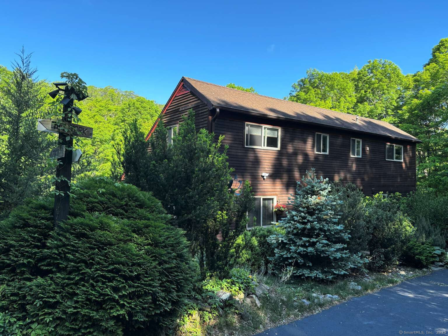 Imagine waking up surrounded by your own private 3-acre forest, stepping out your door onto miles of preserved trails - yet still being only minutes from top-rated Ridgefield schools and an easy commute to NYC. Welcome to your Ridgefield sanctuary. Well-maintained 3-bedroom 2-bathroom home offers 2600 sq ft of living space including a daylight finished basement. The living room impresses with a high ceiling and skylight. While the home offers three bedrooms, each is exceptionally spacious-measuring approximately 235, 201, and 195 sq ft-with generous walk-in closet space. Unlike many listings, all photos are recent and unedited.  All major systems-roof, heating, cooling, water, septic, electrical, and plumbing-are in excellent order. Clean and turnkey. 570 sq ft garage offers space for 2 cars and work area. Features include a cozy wood-burning insert, mini-split AC/heating, hardwood floors, remodeled bathrooms and interior, fiber-optic internet. All modern appliances (2 refrigerators, oven, dishwasher, washer/dryer, microwave) are included as well as 9.4KW generator, snow blower, and home security system. Water tank replaced in 2025.  Relax on 450 sq ft deck, play on the pro-grade basketball court, explore the Ninja Warrior course, or garden in the greenhouse. Stay stocked with a large firewood shed.  Just 15 mins to Ridgefield center, Brewster train, and Martin Park Beach.  Additional features included in photo gallery.