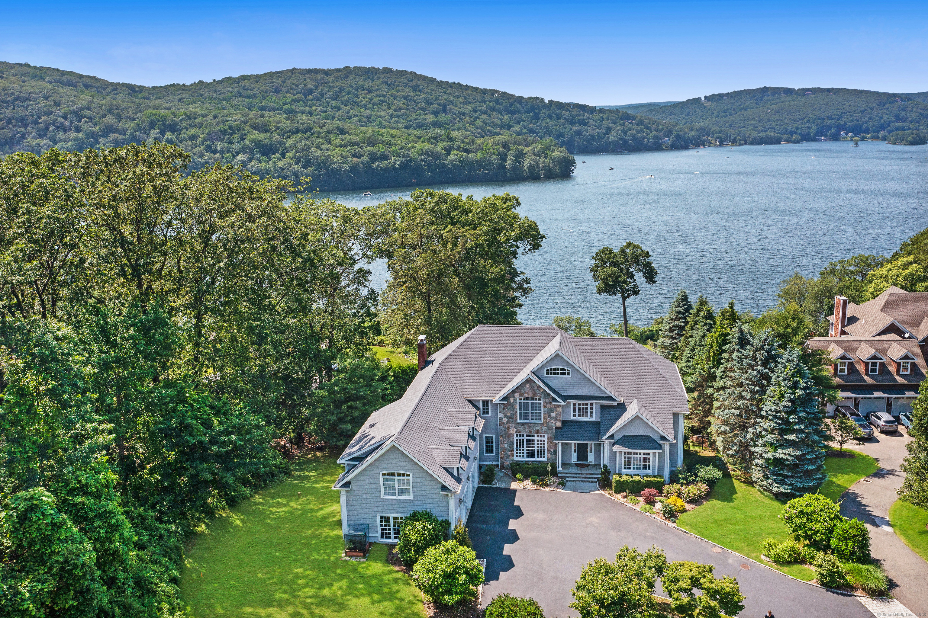 Welcome Home to this incredible lakefront oasis! Exclusive access to Candlewood Lake awaits you at this pristine, elegant masterpiece. Spectacular views abound from every room of the spacious, yet relaxed home. The open-concept main level includes a vaulted living room, resplendent dining room, comfortable great room with floor-to-ceiling stone fireplace, stunning office with built-ins and mirrored cabinetry, and a bright kitchen equipped with everything a chef would want for gourmet entertaining incl professional appliances, huge center island and wine cooler, plus multiple French doors lining the rear and allowing access to the expansive deck. Rounding out the main level is the primary suite with smashing views, spa-like bath and 2 walk-in closets. Upstairs, 3 private bedroom suites and a multi-purpose bonus room make for comfortable living. Additional entertaining space is found in the walk-out lower level. The unmatched outdoor living space, including the expansive deck, stone patio, rolling lawns, 40x20 Gunite pool, firepit, outdoor kitchen, professionally landscaped gardens and private dock, combine to create the perfect place to relax and enjoy boating & floating in CT's "best kept secret". This wonderful property has countless amenities and has been tremendously cared for incl a new roof. Pride of ownership abounds and it's simply ideal for the lucky next steward of this residence! An hour from Manhattan via Metro North, a true getaway from the everyday. Welcome Home!