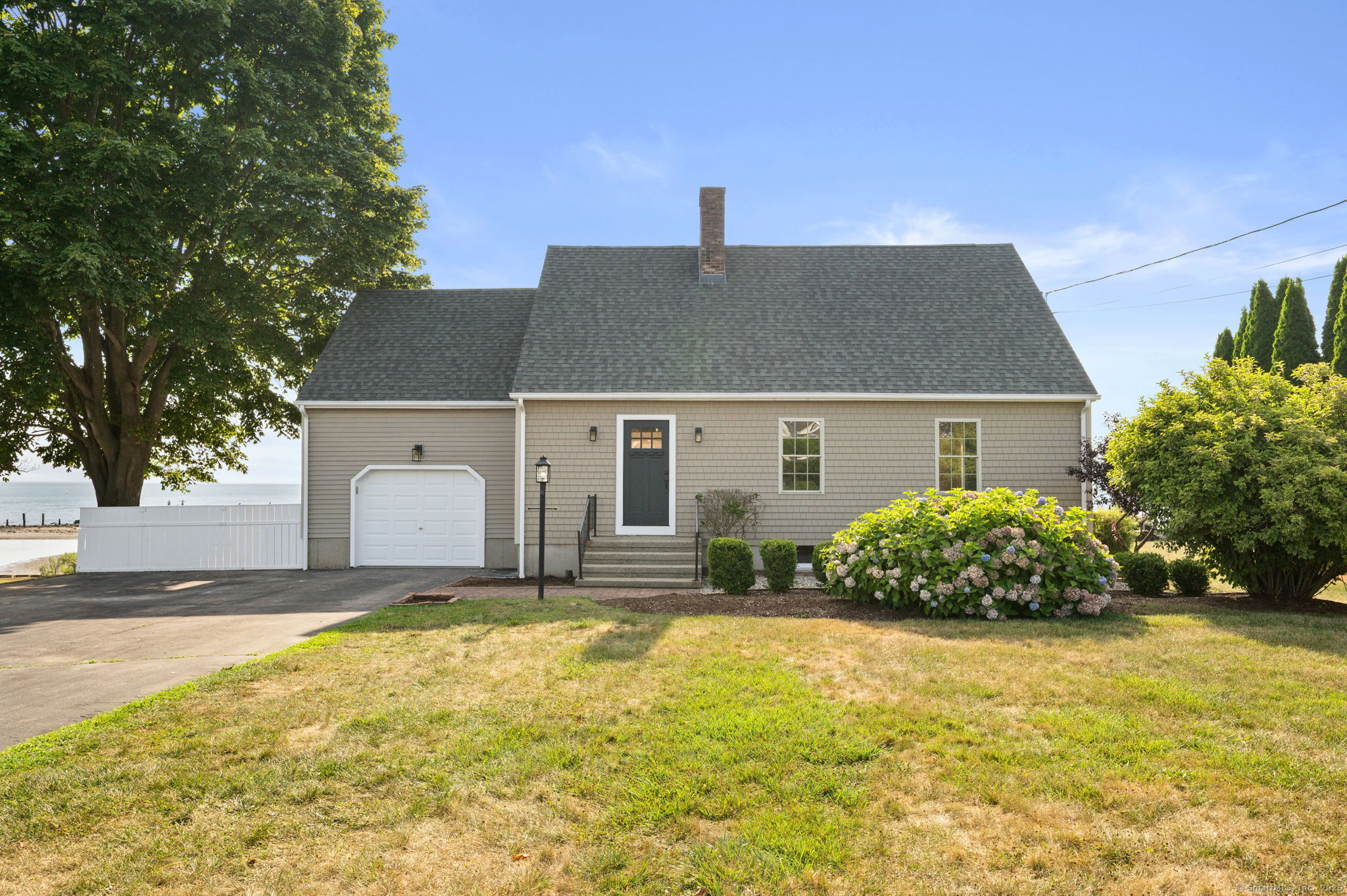 Most New Englanders will tell you that one of the hardest aspects of living here is when summer comes to an end. Good news: your summer will never end when you can step out of your exceptional waterfront home and onto the beach, any time of year! Welcome to 25 Division St, a beautifully remodeled 3/4 bedroom Cape with year-round waterfront views & direct access to Jordan Cove & the LI Sound. Stepping through the front door & into the herringbone tiled foyer, you'll immediately be drawn into the family room with a fireplace for colder nights, & a slider leading onto the custom multi-level Mahogany deck with panoramic ocean views. To the right of the family room is an open concept gourmet kitchen with soft-close cabinetry, marble countertops & backsplash, complete with brass fixtures, stainless steel appliances, & large pantry for added storage. Refinished gleaming hardwoods flow through the kitchen, living, dining, & family rooms. The main level is finished with a full bath with stand-up shower with floor-to-ceiling tile for washing off the sand, & access to a one-car garage. Upstairs you'll find 2 well-appointed bedrooms, another full bath with shower/tub combo with custom ocean blue tile surround, & vanity with quartz countertop. The primary bedroom also leads to a large dormered 21'x16' unfinished space which could eventually complete your primary en-suite with a full bath & walk-in closet (among other options).