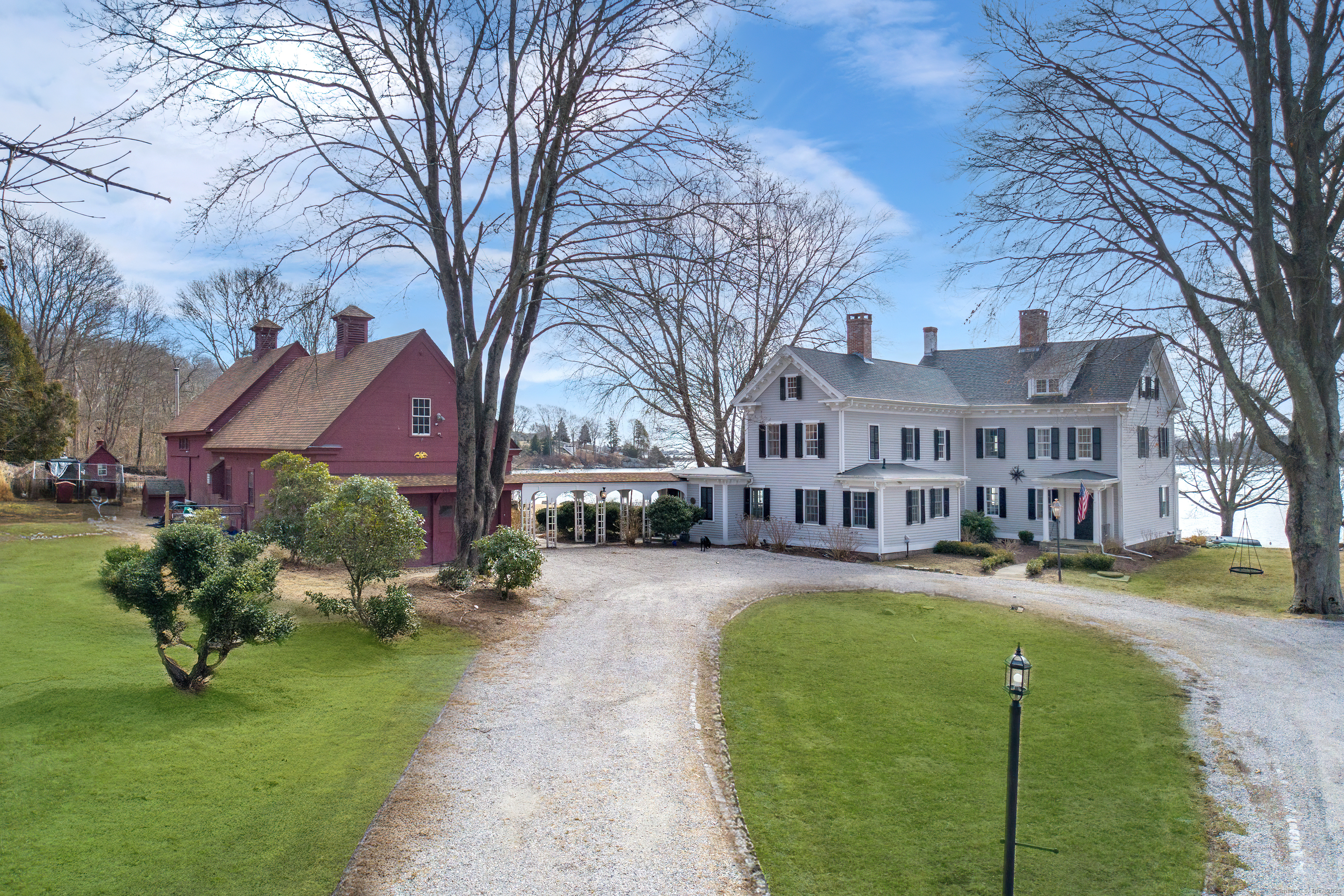 Esteemed shipmaster Captain Silas Beebe created an enduring legacy at this 19th-century gentleman's farm with 524' of Beebe Cove frontage. Extensive renovations preserved the historic grandeur while incorporating modern updates. The waterfront grounds, featured in major motion pictures including a Hallmark classic, are anchored by the restored chestnut barn, heirloom gardens, specimen trees, and grand hardscape. Banks of roses and extensive hydrangea frame the grounds and stone walls leading to a heated pool. The backdrop with the adjacent barn creates a magical entertaining area. Inside the main home, extensive millwork - pumpkin pine paneling, built-ins and detailed moldings are found throughout. A spacious eat-in kitchen with butler's pantry opens to a formal dining room overlooking the cove, and the adjacent living room and parlor provide comfortably elegant gathering spaces. Nine fireplaces, several in use, offer winter ambiance. Upstairs, a central den connects three en-suite bedrooms including the primary with dressing area. The third floor, once maids' quarters, offers two bedrooms, full bath and sitting area. The guest house was rebuilt in 2022 echoing the home's character with high end updates including marble baths. Abutting Avalonia Preserve, the grounds slope to a private dock, a remnant of the ice harvesting trade and the pristine cove. A seldom found legacy property. Stunning. 2.5 hours to Boston/NYC, and a stone's throw to downtown Mystic and Noank.