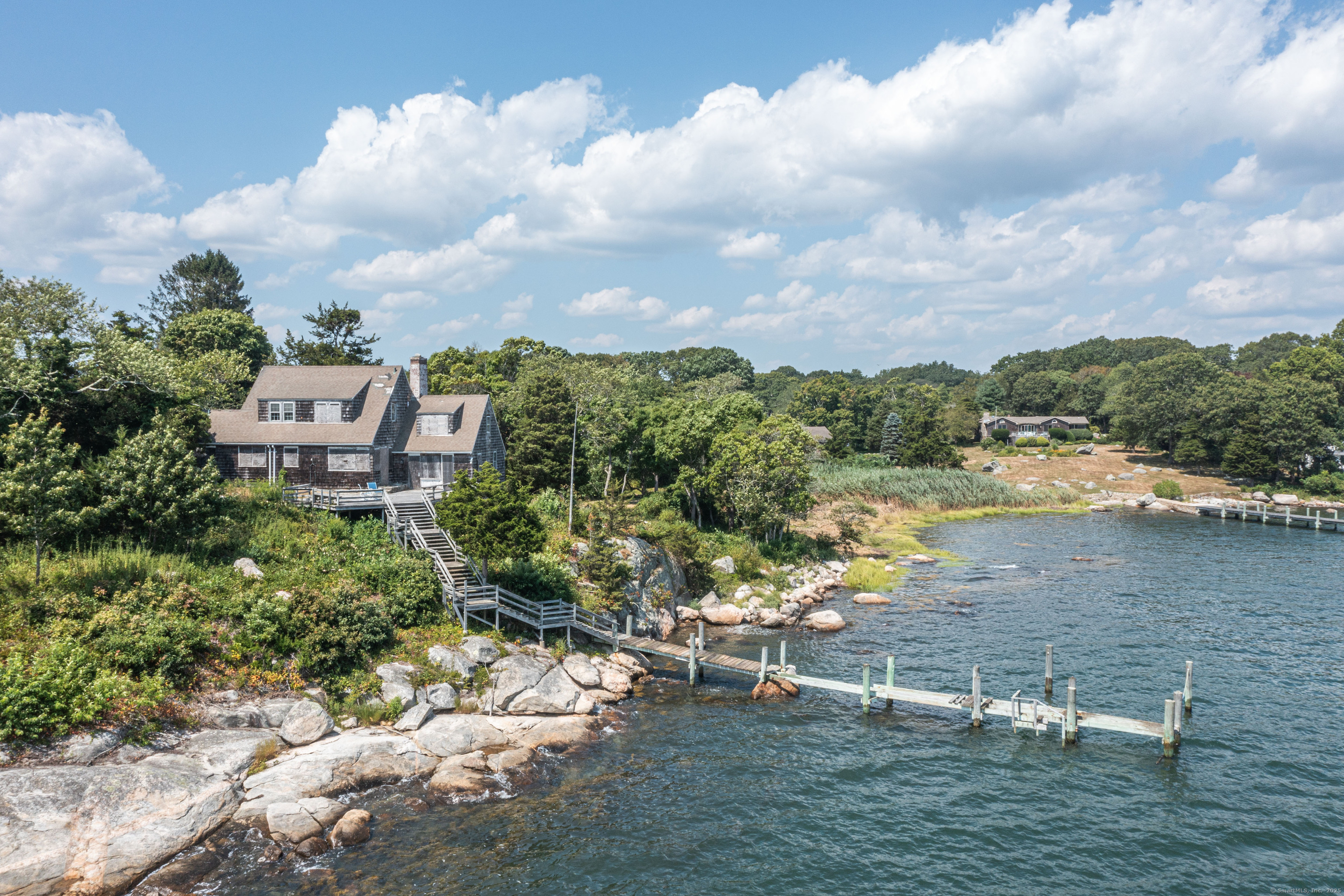 Magnificent Direct Waterfront with Unobstructed Water views and Private Deep Water Dock. All nestled on 1.24 Acres with 201' of Direct Water Front. Rare and Unique setting with views to Fishers Island Sound, Enders Island, Stonington and beyond. The drive from the road entrance rises and winds gracefully past tall pine trees and mature plantings to the 28' elevation where the existing home structure is located. This exceptional parcel offers a once-in-a-lifetime canvas for your custom-designed coastal retreat.   Enjoy your private fixed dock with appx. 4 1/2 ' of water at low tide, and appx. 6' at high tide. Mean Low Tide in the immediate adjacent water is 7'.  This property is located in a very private sector of Mason's Island, southwest of the fresh water pond. This existing house should be removed and rebuilt to your specifications. There is also a 2 bay garage structure at the entrance to this property. This incomparable property has been owned by only two families in the past 103 years. Awaken each morning to sweeping water views, spend your days sailing, boating, kayaking or simply basking in the serenity of this private island sanctuary, and hear the breaking waves. With year-round access to the beauty and recreation of the water, this is more than a homesite - it's a dream come true. 37 Nauyaug Point Road has First Right of Refusal to purchase the adjacent 33 Nauyaug Point Road which is also available for purchase with 1.64 Acres and 230' of waterfront.