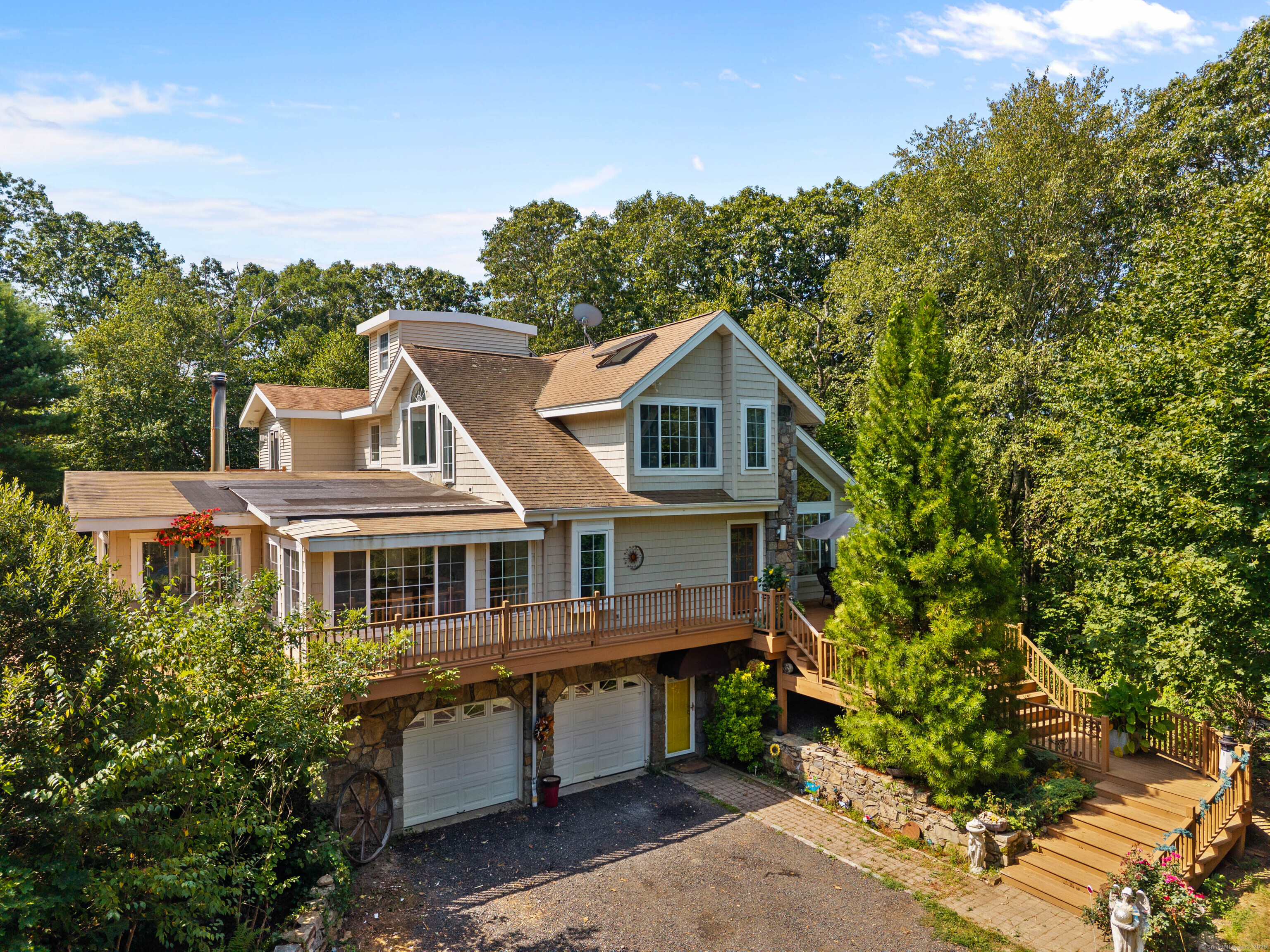 Gracefully perched above its 1.87-acre lot, this striking custom-built contemporary home offers elevated privacy, expansive views, and exclusive access to an additional 40 acres! The owner of this residence is one of five property owners who jointly own 20 acres and has access to an additional 20 acres, including an open field ideal for entertaining. Designed with comfort and style in mind, this residence features 3 bedrooms, 3.5 baths and a two-car garage. The interior showcases a bright, open layout centered around a spacious kitchen and dining area. The kitchen includes a large island with cooktop, reddish brown granite countertops, a breakfast bar, a separate prep area, and a comfortable breakfast nook. The dining room, family room, and living room open onto a beautiful wraparound deck, ideal for entertaining or enjoying peaceful mornings and evenings. The living room features two story windows, hardwood floors, a stunning stone fireplace, skylights, and a staircase leading to the upper level. An interior balcony overlooks the living room, adding architectural elegance and openness. The main level includes a full bath and a bedroom with convenient access to shared spaces. On the upper level are two bedrooms, including 2 primary suites with private baths. One suite offers a private balcony with peaceful views. The lower level includes a half bath and a 4th bedroom, perfect for guests or a home office. This beautiful home offers quiet living surrounded by natural beauty.