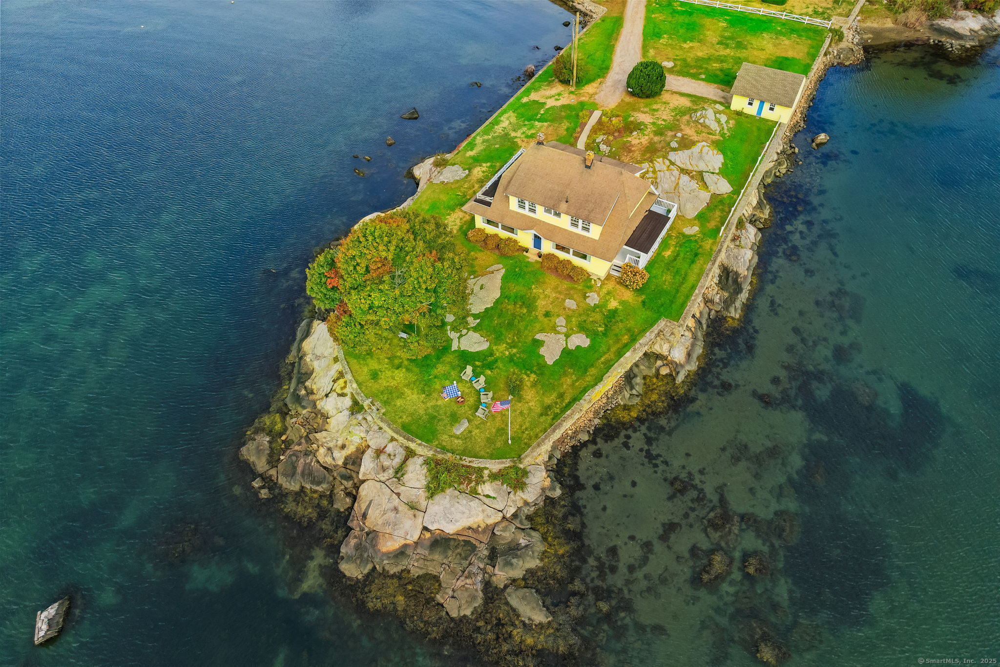 RARE OPPORTUNITY! Perched proudly on its own peninsula and surrounded by water, this 1920 Dutch Colonial Revival home offers a unique blend of timeless architecture, historic charm, and breathtaking natural beauty. With its signature gambrel roof, gabled dormers, and classic symmetrical design, the home enjoys sweeping views over Fishers Island Sound from nearly every room. Lovingly maintained by the same family since 1984, this residence reflects care, pride, and authenticity throughout.  Just a stone's throw from Esker Point Beach and Noank Village, and only minutes to Groton Long Point, Downtown Mystic, Stonington, and more. This location combines coastal tranquility with convenient access to shopping, dining, and marinas. With ample square footage, 2 car garage, and an unparalleled waterfront setting, the property offers endless potential to create your forever home. Ideally positioned between New York City and Boston, this remarkable home embodies the best of New England's coastal living; a true sanctuary where history, character, and scenery come together in one extraordinary place.