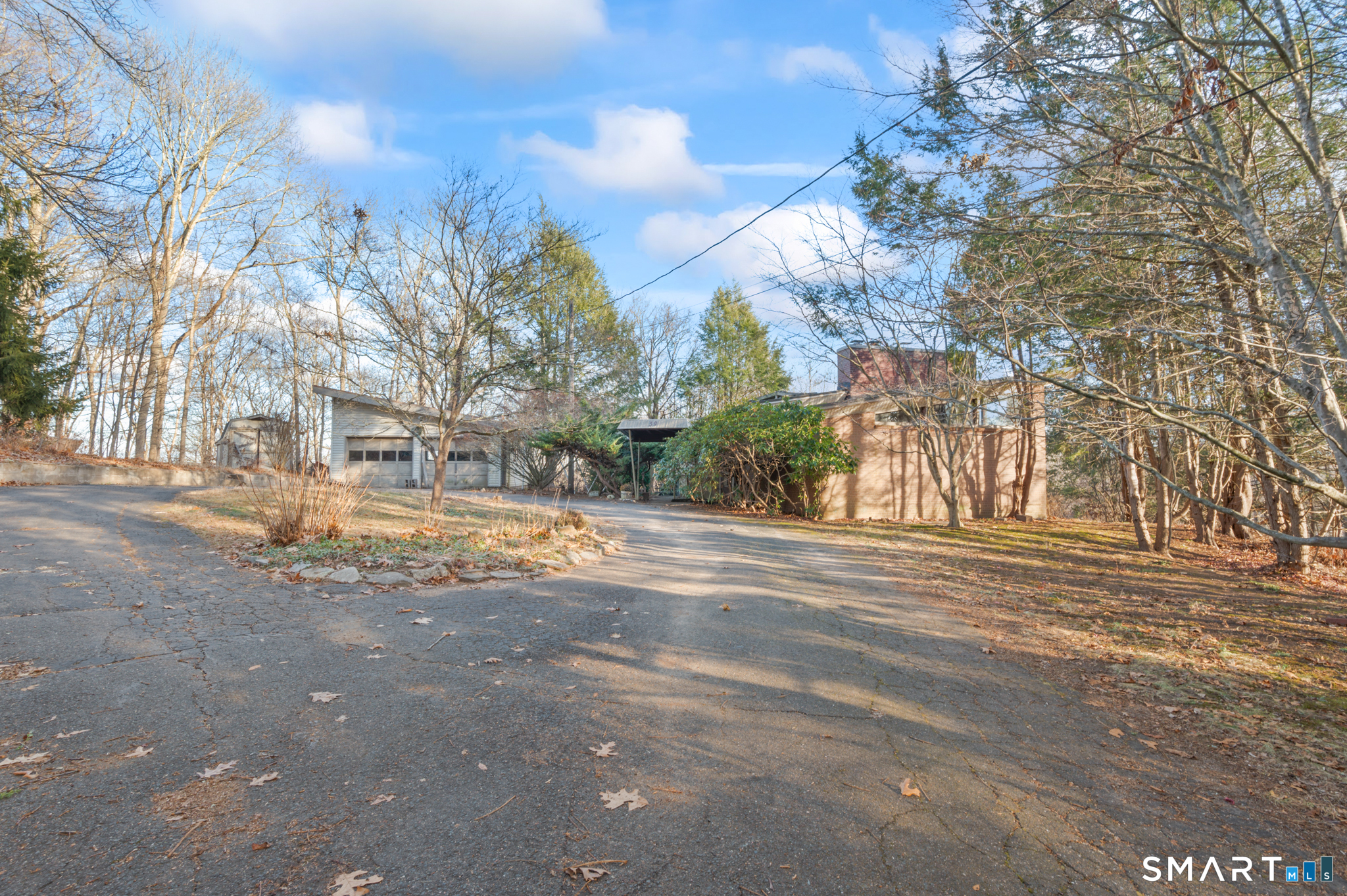 Authentic Mid-Century Modern retreat set on over 3 private acres, this truly one-of-a-kind home celebrates timeless design and architectural integrity. Original finishes remain beautifully intact, highlighted by soaring vaulted ceilings and dramatic two-story windows that flood the home with natural light and offer seasonal views of Andover Lake. True to its mid-century roots, the home features fascinating yet highly functional details, including hidden compartments, custom built-in storage, and thoughtfully designed display casings throughout. A stunning library with a classic step ladder and cozy reading nook is bathed in sunlight from the expansive two-story windows, creating an inspiring space for relaxation or study. The open-concept living and dining areas are framed by walls of glass and vaulted ceilings, delivering a seamless flow and an airy, light-filled atmosphere. Solid steel beam construction adds both architectural distinction and enduring strength, blending form and function in iconic mid-century style. Additional highlights include a deck with seasonal lake views, green house, sauna, a detached two-car garage, and a circular driveway that enhances curb appeal and convenience. This remarkable property is a rare opportunity for mid-century modern enthusiasts and must be seen to be fully appreciated. Home sold AS-IS.