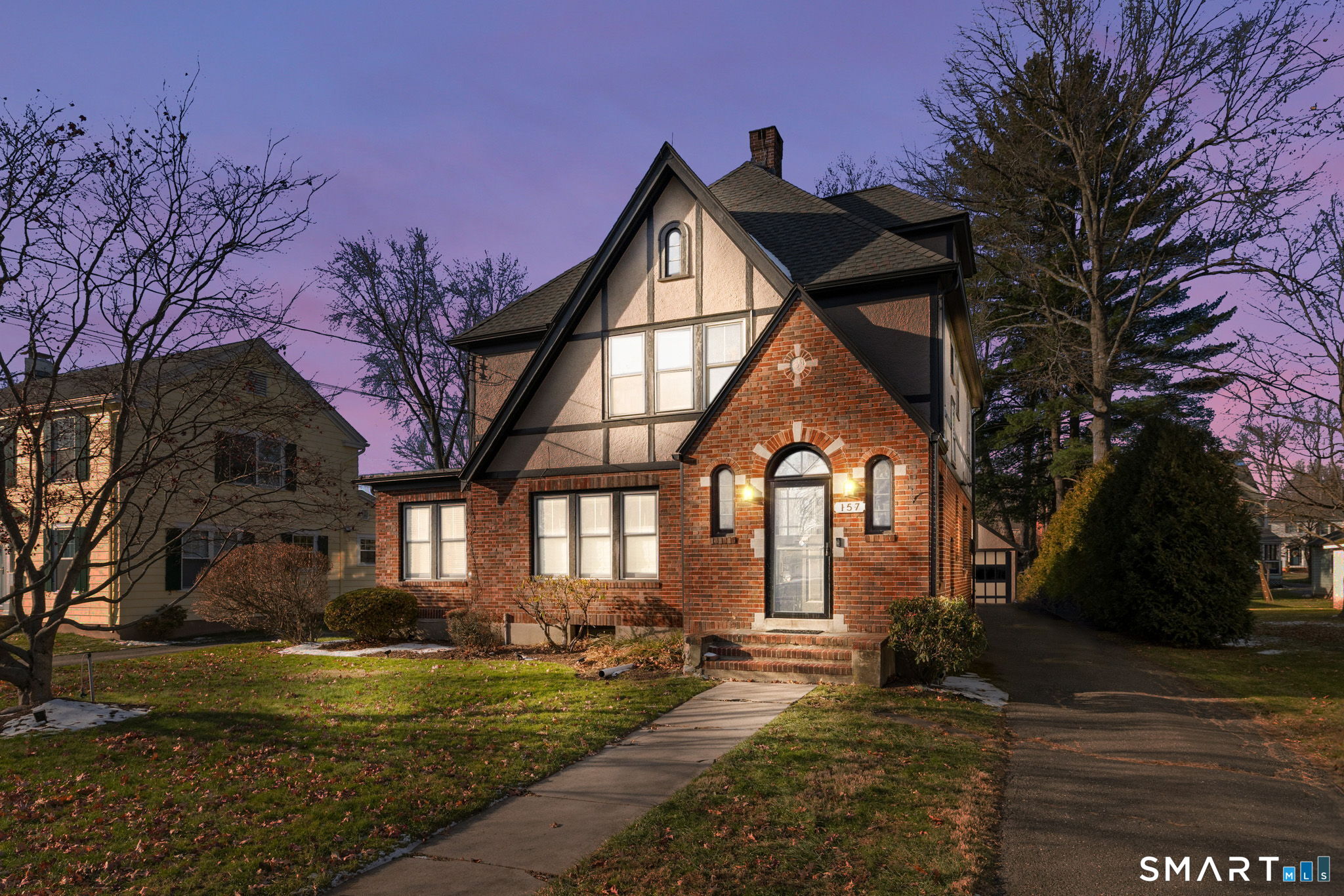 Set along one of West Hartford's most charming streets, 157 Four Mile Road is the kind of home that feels pulled straight from the pages of a design magazine. A classic Tudor Colonial exterior sets the tone, blending brick and stucco with timeless curb appeal and a welcoming presence from the moment you arrive. Inside, the home unfolds with warmth and intention. Sunlight dances across rich hardwood floors, while tall ceilings and crown molding run throughout the living room and dining room. The living room centers around a beautiful fireplace and flows effortlessly into adjacent spaces through elegant French doors, making it ideal for both everyday living and entertaining. A gracious dining room invites memorable gatherings, while the thoughtfully designed kitchen offers a true chef's experience with granite countertops, a breakfast bar, and premium finishes that balance function and style. Upstairs, the bedrooms feel serene and inviting, offering flexible options for rest, work, or creative space. Outside, the level yard and patio provide a peaceful setting for outdoor dining or quiet mornings with coffee. With classic architecture, thoughtfully curated interiors, and an unbeatable location steps (a .7 mile walking distance) from Blue Back Square & West Hartford center, offering shopping, dining, and easy commuter access. This Four Mile Road home delivers timeless character with modern comfort in one of West Hartford's most desirable neighborhoods.