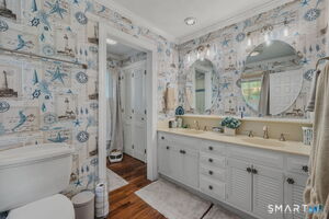 Master bath with twin sinks, walk-in shower and vintage marine wallpaper.