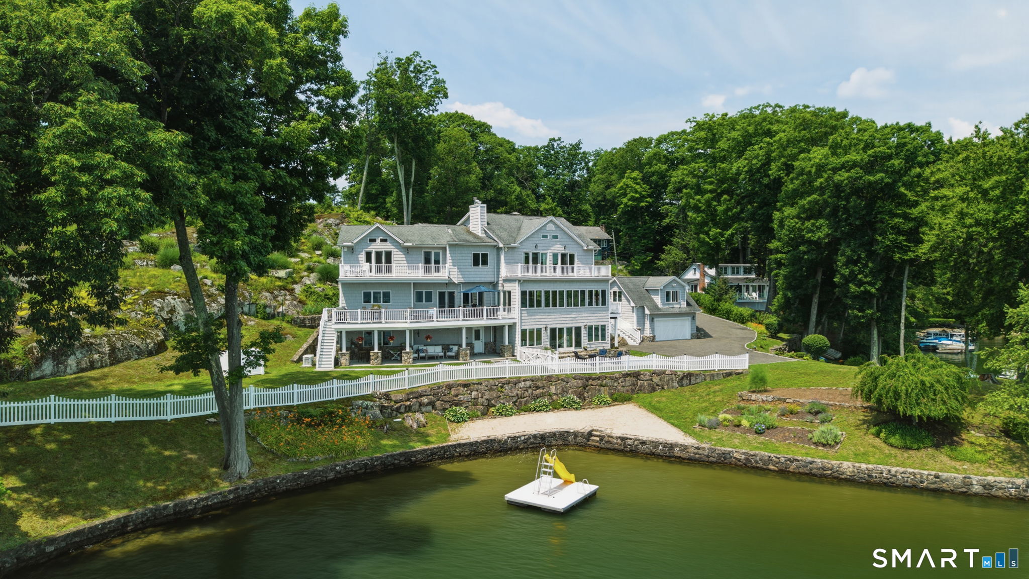 Welcome to lakefront living at its finest on Candlewood Lake. Set on a private, level waterfront lot with over 450' of shoreline, this exceptional 3-bedroom home, rebuilt in 2006, offers breathtaking panoramic views and more than 6,000 SF of living space in one of the lake's most coveted settings. Designed for comfortable living and entertaining, the spacious main level flows seamlessly from inviting living and family rooms into an open kitchen and dining area. Generously sized rooms throughout provide comfort and flexibility, while every room enjoys stunning water views, creating an extraordinary connection to the lake. The lower level offers additional living space ideal for guests, fitness, hobbies, or entertaining, with direct access to the outdoor living areas and waterfront. Outside, professionally landscaped gardens frame the property and create a beautiful backdrop for lakeside living. Relax on the patios, enjoy the private dock, or simply take in the ever-changing scenery. The level shoreline provides effortless access to the water, a rare and highly sought-after feature on Candlewood Lake. Just 75 miles from Manhattan, this remarkable property offers the perfect balance of peaceful waterfront living and convenient access to New York City. A detached garage with bonus space above provides added flexibility. Located in the sought-after Hollywyle community, this is more than a home-it's a rare opportunity to experience the very best of Candlewood Lake.