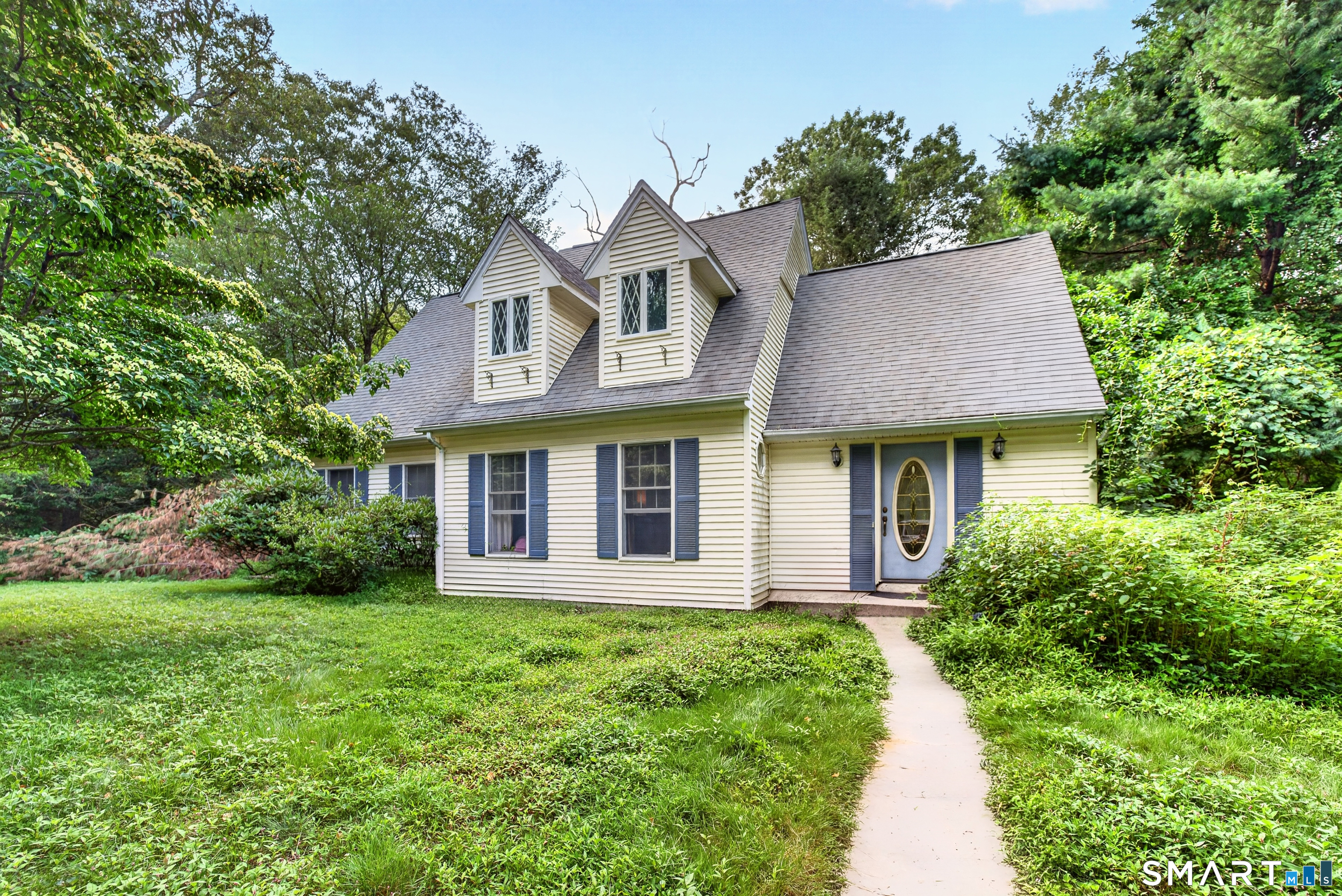 Welcome to 26 Bush Hill Road, a charming Cape Cod tucked into a private, wooded 3.8-acre setting in Brooklyn. Offering approximately 1,472 square feet, this three-bedroom home features a flexible layout with a first-floor primary bedroom, first-floor laundry, and two additional spacious bedrooms upstairs. The updated kitchen includes crisp white cabinetry, bright countertops, and stainless-steel appliances, while the inviting living room offers plenty of natural light and an open staircase. At the rear of the home, the impressive dining area is surrounded by windows and features a vaulted ceiling, fireplace, and French doors leading outside. With generous room sizes, hardwood flooring, two bathrooms, and an expansive wooded lot offering privacy and room to enjoy the outdoors, this home combines comfortable everyday living with a peaceful country setting.