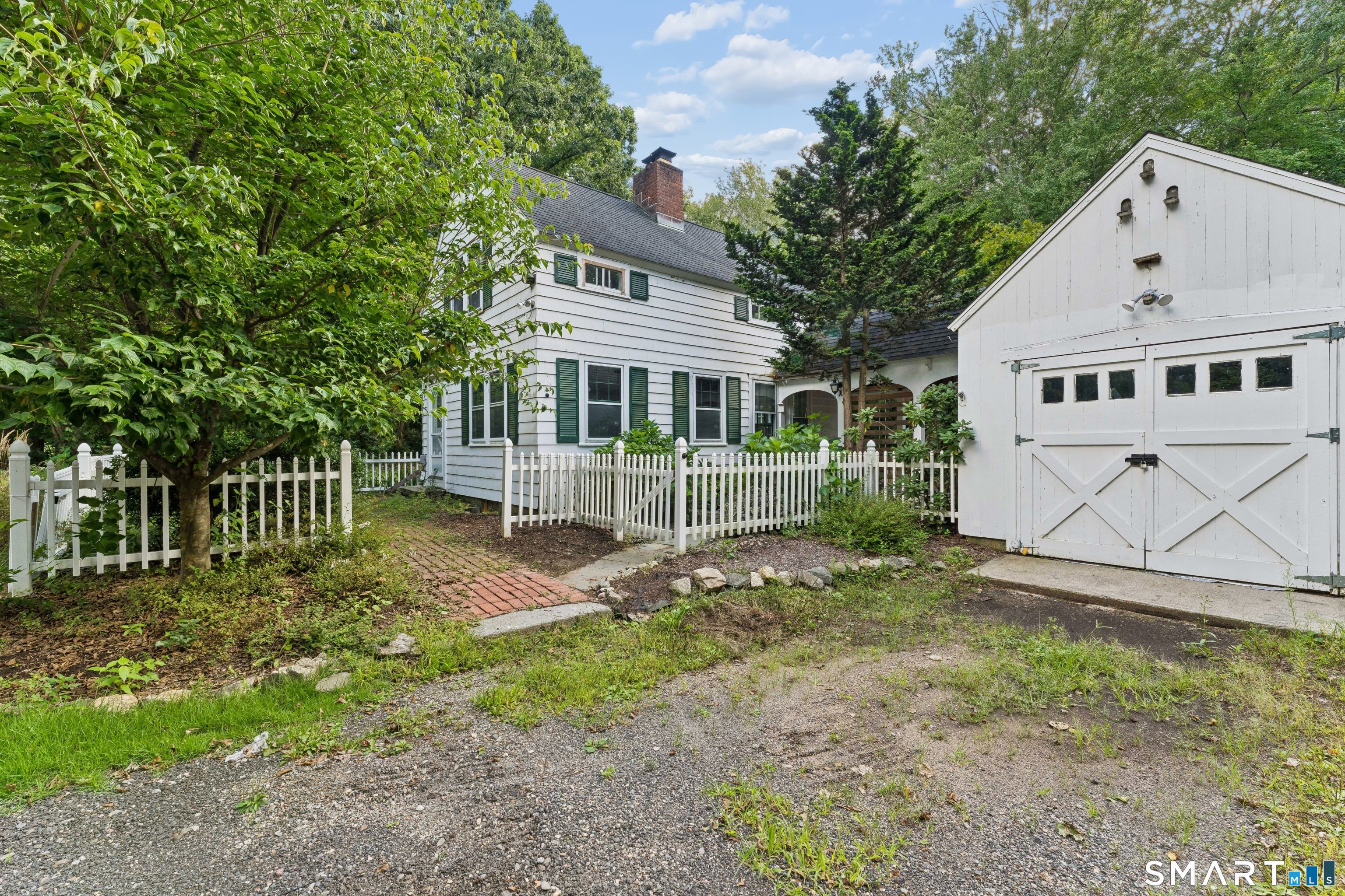 170 South Main St in Newtown is now available for sale. This mid century 2 bedroom Cape Cod has maintained period charm in a cozy nook off South Main Street. The homes front entrance is through a white picket fenced garden and delivers you into the living room which has beautiful wide board floors and tongue and grove walls surrounding a brick fireplace and built-ins. Through the living room you enter a quaint kitchen with a second exit to the breezeway connected to the garage. On the interior side of the kitchen you can exit to the basement with all updated furnace, water heater etc. and an additional exit to the backyard and fieldstone patio. The upper floor continues the rustic wood theme into 2 bedrooms and a full bath. There are variety of upgrades that can be made to the 1.85 acre property for a first time buyer or those with talent for DIY projects. The detached garage offers exciting possibilities beyond traditional storage. With its separate setting from the main residence, this versatile space could make a wonderful artists studio, creative workshop, hobby space, home office, or personal retreat. Bring your imagination and transform it into a space that perfectly complements your lifestyle.