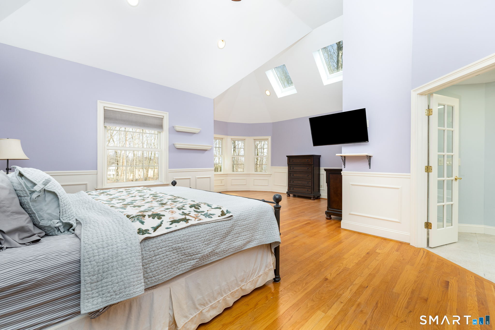 The primary bedroom, at 23' x 23'9" is a suite including the upper level of the turret. It has vaulted ceilings, skylights, oak floors, panel wainscotting, multiple closets and French doors to the ensuite bath.