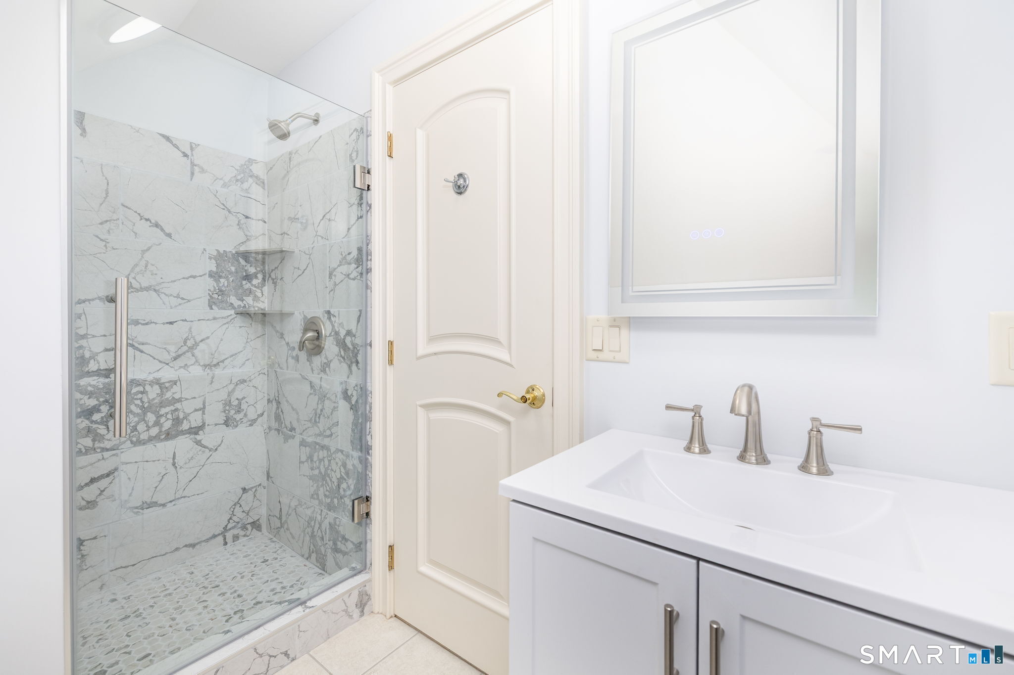 This en-suite bath has been remodeled with gorgeous marble tile shower and new LED mirror.