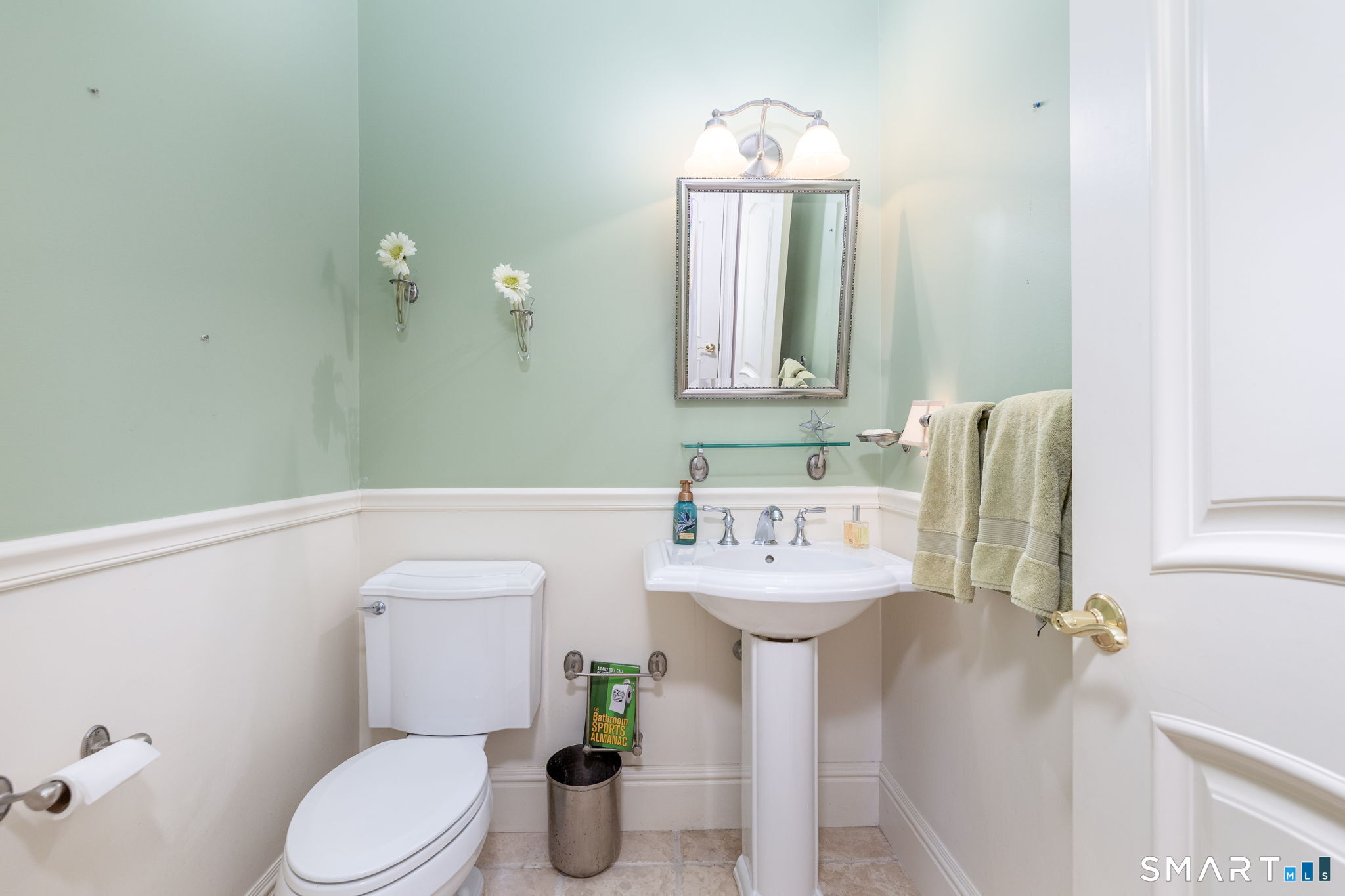 The 1st floor half-bath is located in the mud room area near the garage, across from the laundry room. The laundry room has a linen closet, cabinets, drying racks, a laundry chute from the 2nd floor, and is plumbed for a laundry room sink.