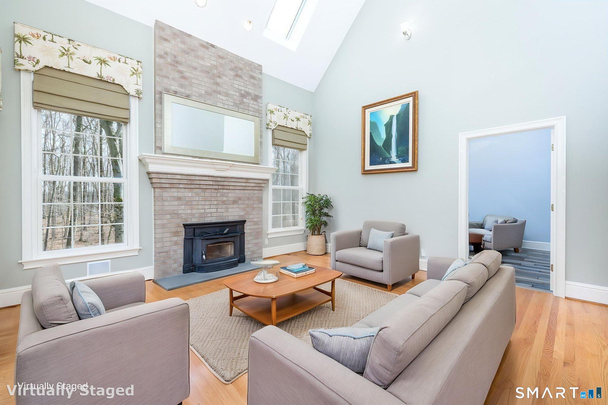 The 15'10" x 16'1" family room features a floor-to-ceiling fireplace with custom mantle and wood stove insert for cozy nights, plus refinished oak floors, vaulted ceiling, oversized windows, ceiling fan, and skylights.