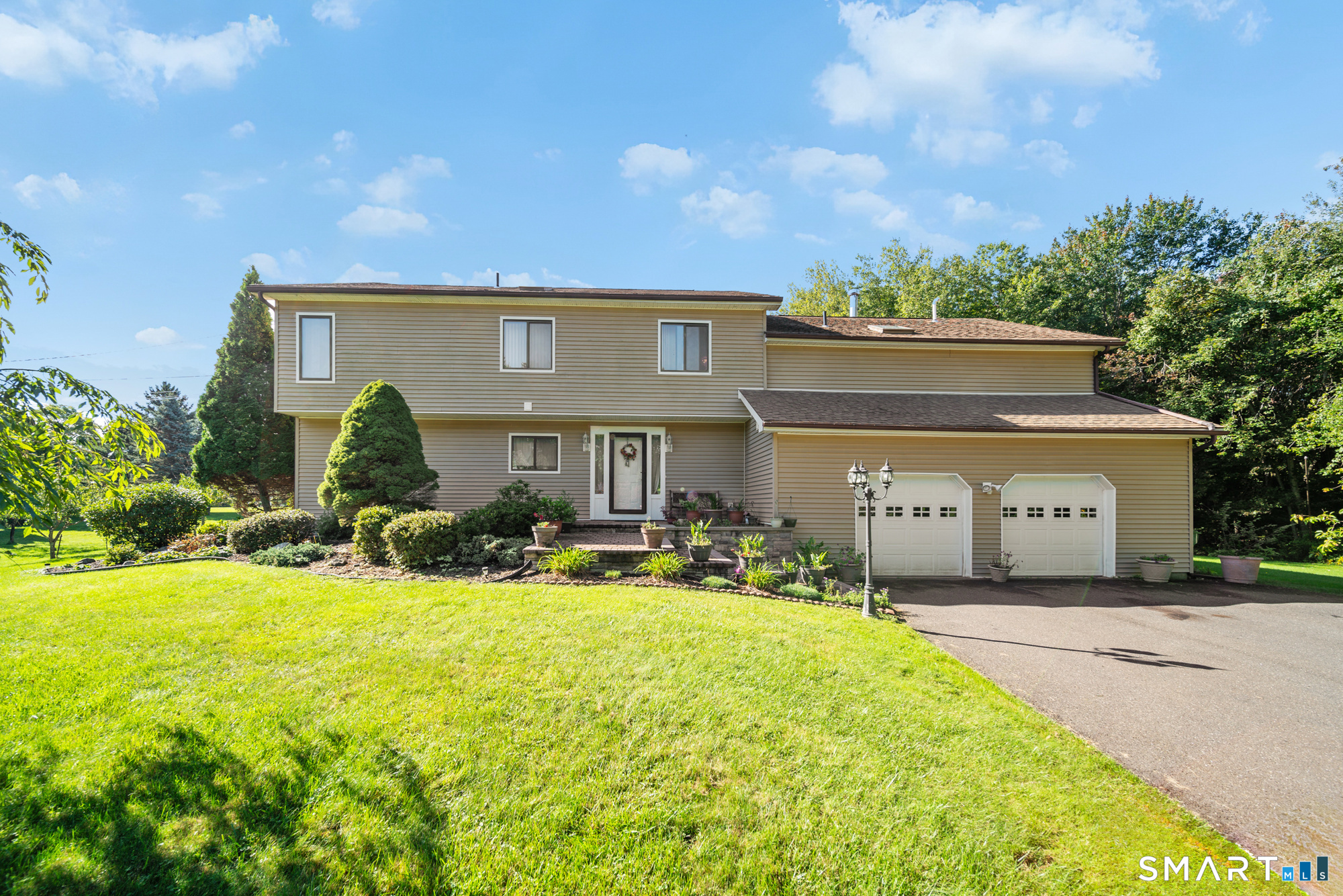 This spacious contemporary home offers a unique combination of open living spaces, abundant natural light, and privacy. The open floor plan features soaring ceilings, a south-facing wall of windows, and beautiful hardwood floors throughout. The four-level design provides an exceptional amount of living space, including a living room on each level. The main living area features a sunken living room and custom built-ins, creating a warm and distinctive gathering space. The home offers four bedrooms, including a spacious primary suite with a vaulted ceiling. The luxurious ensuite bathroom features a Jacuzzi tub, separate shower, and an extra-large walk-in closet. Additional highlights include a custom hair station with wash sink, a large deck, and a two-car garage located beneath the home. Outside, enjoy excellent sun exposure, mature fruit trees, colorful flower gardens, and a large garden area. The rear yard includes a level open field-ideal for outdoor recreation, sports, gardening, or simply enjoying the privacy and natural surroundings. This is a truly distinctive property offering space, character, and privacy in a one-of-a-kind setting. Agent is related to the seller.