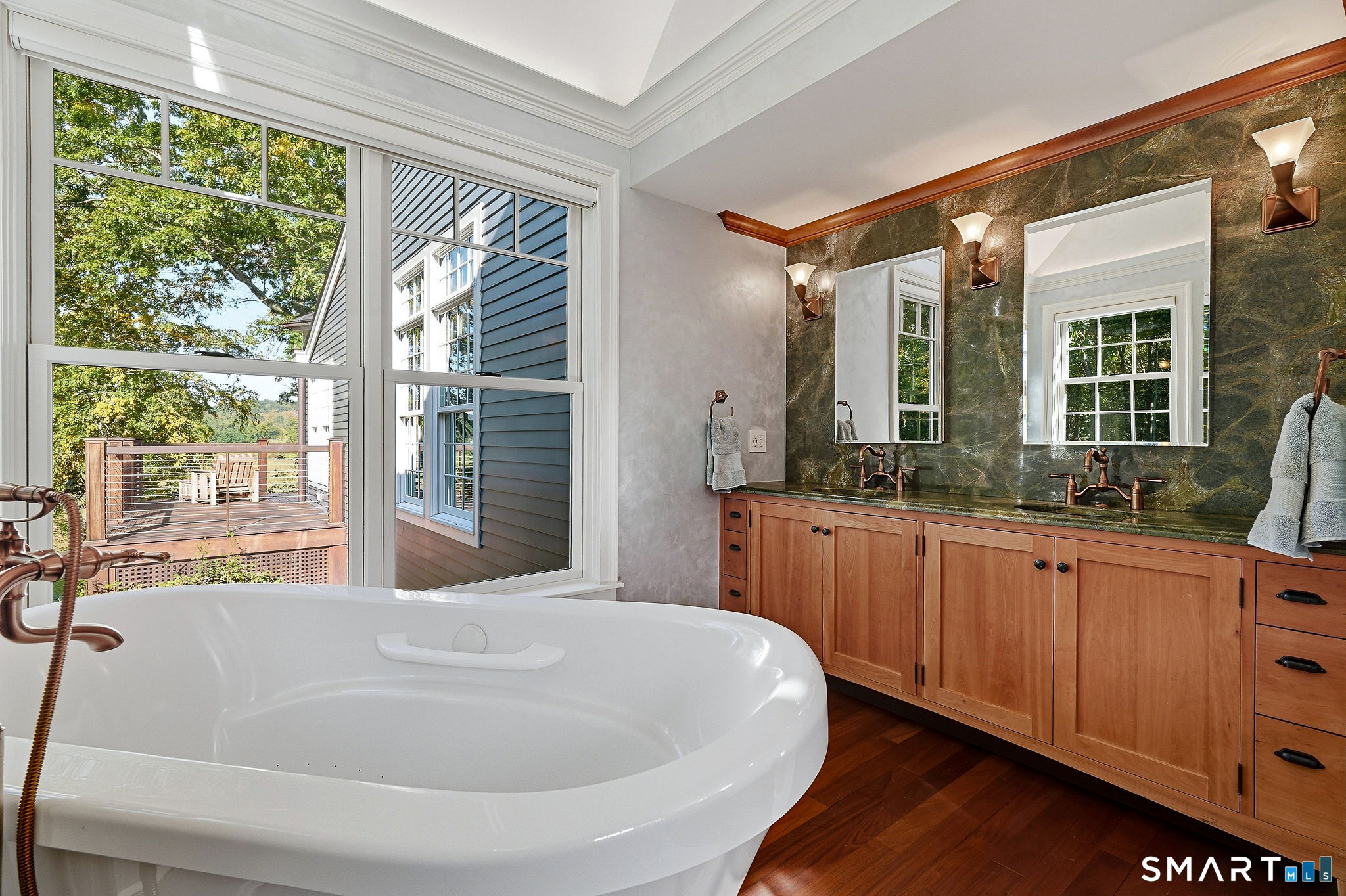 Granite topped cherry vanity and a tub with a view