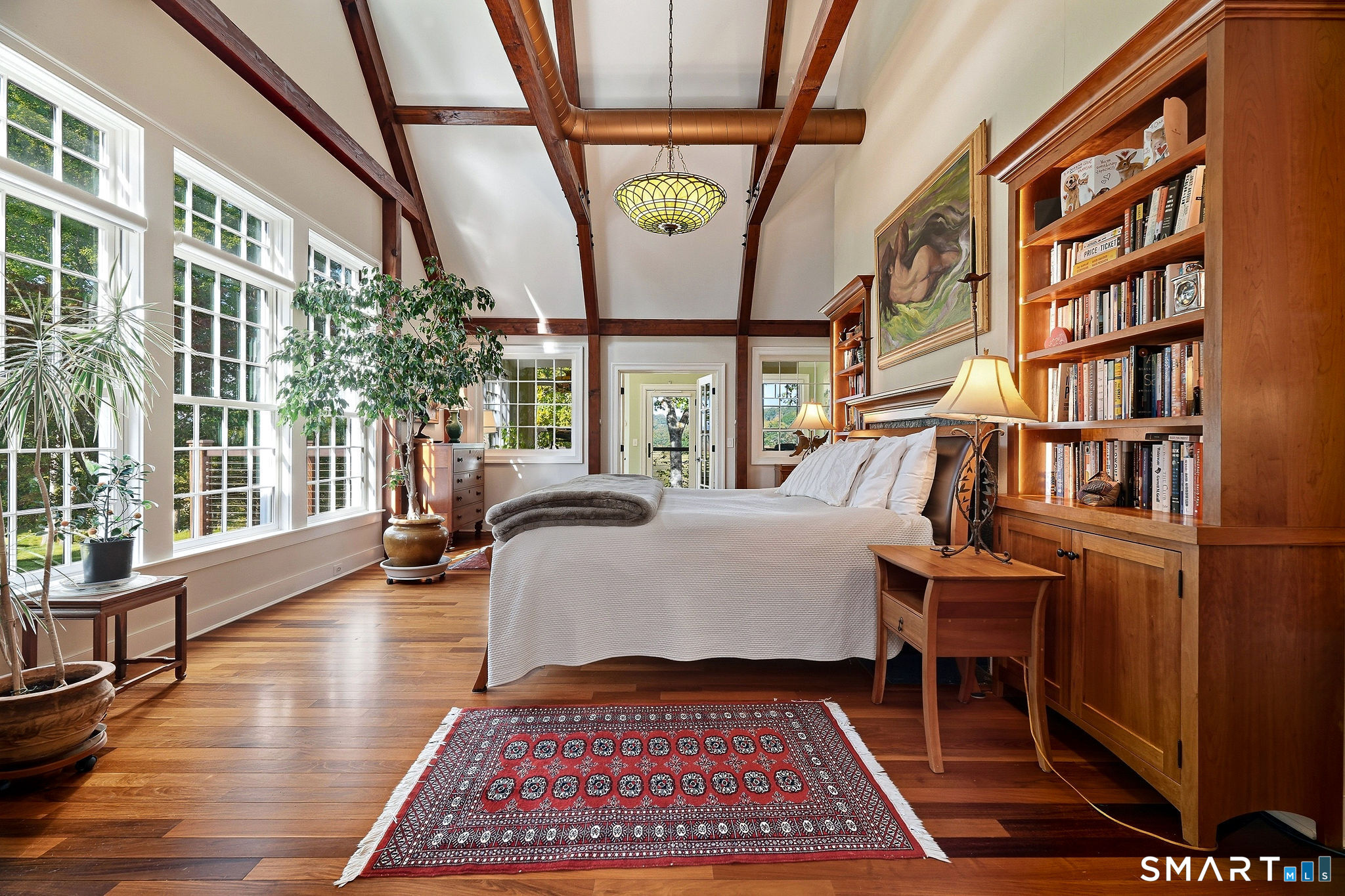 Main level primary bedroom with beamed ceiling, office and deck access