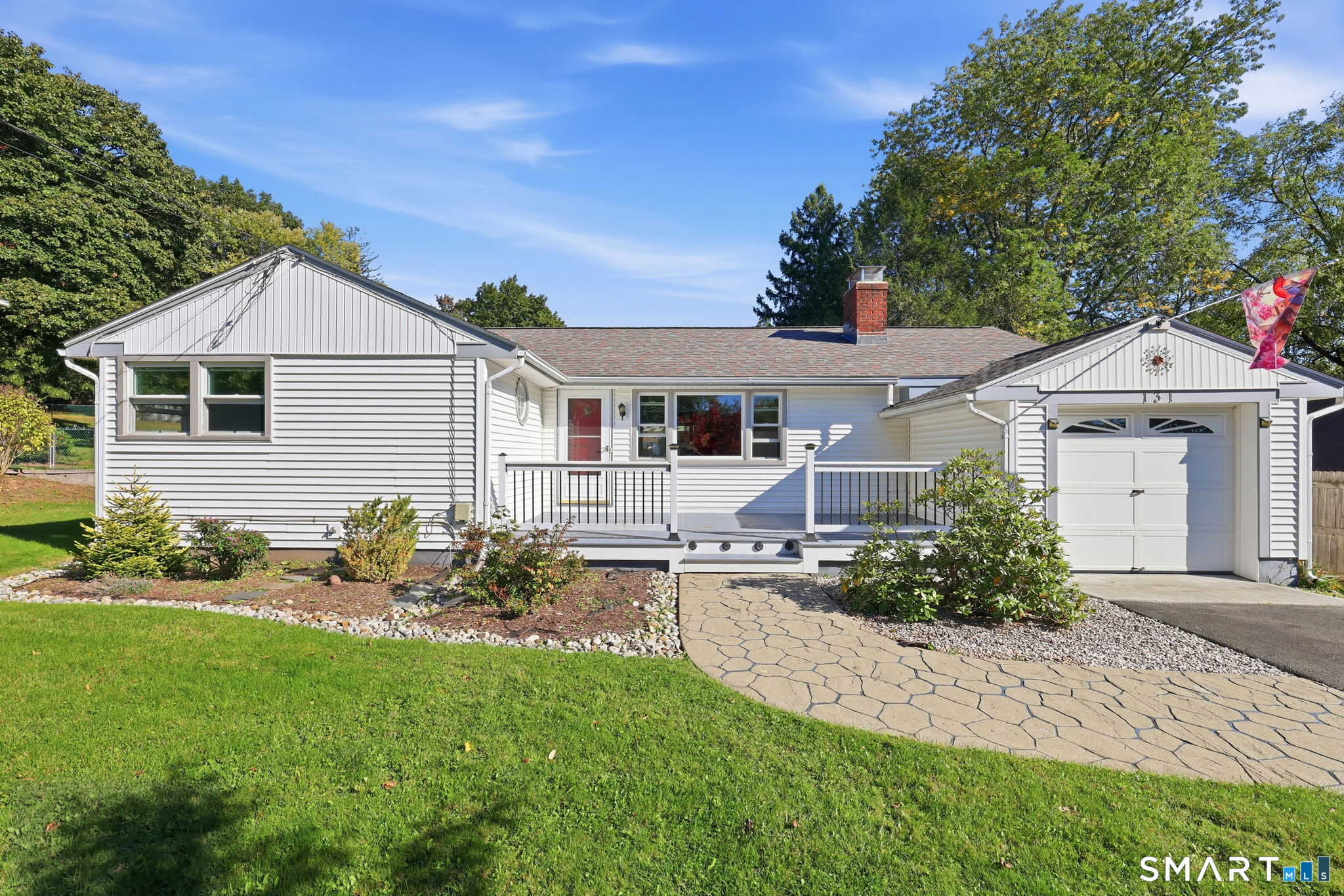 An expansive deck, a generously sized backyard, and sunlit interiors make 131 Avery Street a standout opportunity along Manchester's South Windsor town line. This expanded ranch offers outdoor space that invites you to linger, from morning coffee and container gardening to dinners on the deck and gatherings in the yard. Built-in plant stands add a distinctive touch, while sliding doors from both the dining room and primary suite connect the home to its beautiful setting. Inside, wood floors extend throughout most of the home, bringing warmth and continuity to the living spaces. A wood-burning fireplace flanked by built-ins anchors the living room. The adjoining dining area features a built-in curio cabinet and opens to the kitchen, keeping the main living spaces connected. A window-lined breezeway off the kitchen offers possibilities as a three-season sitting room. The primary suite pairs direct deck access with a spacious ensuite bathroom and full walk-in shower. Updated windows, a one-car garage, and abundant basement storage add everyday value. A separate basement room offers potential for future finished space. Conveniently located near highways, the mall, and schools, this home brings together room to relax, space to gather, and access to daily essentials. Come explore the backyard and imagine how you would make the most of it.