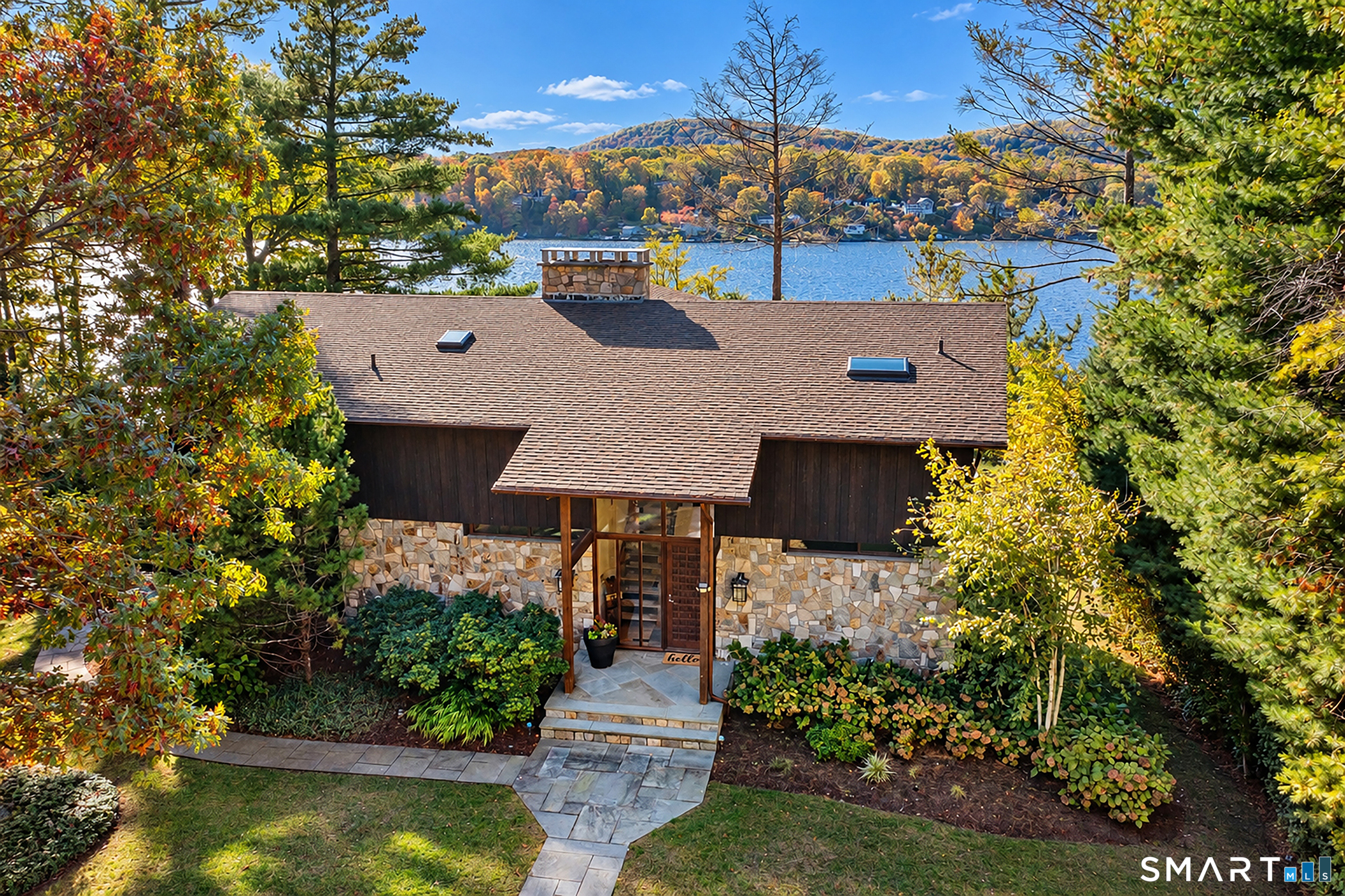 Unique Waterfront Deck House with soaring wood ceilings, post & beam construction, dramatic lake views and over 116 foot frontage on scenic Lake Candlewood. A level stone path leads from the expansive paved parking area w/3 car garage to this stunning contemporary surrounded by perennial plantings: the perfect entrance to this home deigned for a casual lake lifestyle. This deck home flexible floor plan offers many possibilities. A grand great room with walls of windows and stunning floor to ceiling fieldstone fireplace enhances the rustic modern charm. The L shaped kitchen & dining area are ideal for family gatherings and lead through sliders to the expansive deck. The living room is another place for gatherings to watch a movie or enjoy game night. Ascend to the open loft leading to 3 spacious bedrooms. The primary with whirlpool bath is a quiet spa retreat, separated from the other 2 bedrooms w/shared full bath. A spiral stair leads to the lower level with game room, family room with wine barrel ceiling, guest bedroom, full bath & office. Panoramic views, 3 car detached garage ideal for boat storage, a level paved drive and stone stairs and rails down to the lake, this unique lake home combines modern amenities with a true rustic lodge feel. Lakeside decks, Tiki bar & dock. Newer kitchen & baths, central vac, C/A, security & available turn key. Hurry to view this great lake offering! Close to shopping, schools and easy NY commute! Your private lake oasis!