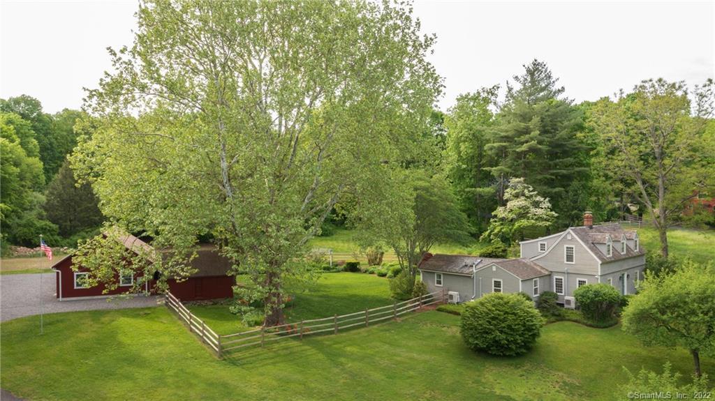 PICTURE PERFECT ANTIQUE CAPE located in the Historic District of Woodbury, part of the National Registry of Historic Places. This home features a stunning backyard with spectacular perennial gardens and is surrounded by split rail fencing. Enjoy the lush greenery with a rainbow of colors popping from Spring to Fall. A first floor wing features a primary bedroom suite, luxurious bathroom, sitting room with custom built-ins and separate entry from outside. This home brings in plenty of natural light with the original divided lite windows. Upstairs there are two bedrooms, each with their own large walk-in closet that lead to a shared custom bath with marble vanity top. The kitchen has high end appliances and includes a professional gas stove/range. A recently renovated hall bath on the first floor includes a custom floating wood vanity and a built-in laundry center, Miele washer and dryer included. The living room is warm and inviting and has a casual dining area/bar space. Head out to the brand new 24 x 50 fully finished office/workshop. This building completed in 2022 features a separate power meter, heating and air systems, commercial sink, hot water, and an ADA compliant  bath. The building is perfect for a home-based business, work from home office, or a recreation space. This property is conveniently located only minutes from the center of Woodbury with a beautiful main street and some of the finest dining in the area. Close to interstate 84 and only 90 minutes to NYC.