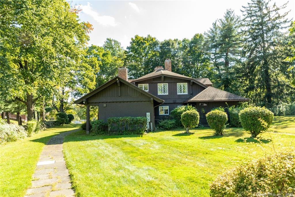 This elegant country chalet sits on over four acres in the highly desirable Country Club neighborhood. Nestled at the end of a private driveway with ancient rock walls, and thoughtfully landscaped grounds, you are invited to this impeccably maintained home. The handsome flagstone wrap-around porch is perfect for alfresco dining. Enter the large open foyer to the feel of yesteryear with today's amenities. The living room spans one end of the home with coffered ceilings, decorative moldings, and fireplace. At the rear of the living room a four-season porch is a perfect getaway for after work cocktail and a good book. At the opposite side of the foyer is your half bath and mahogany walled study with fireplace and built-ins, beckoning you to an after-dinner cigar and bourbon. The formal dining room has gorgeous built-in cabinetry and even a hidden buzzer for the host to discretely signal the kitchen. The large eat in kitchen features granite countertops and eye-catching cabinetry. The back wing of the main level is currently being used as an artist studio, however this could also be a main level bedroom and full bathroom. Upstairs, the large open hallway connects to four enormous bedrooms and three full bathrooms. The master bedroom features a large seating area and updated full bath. Don't miss the two-car garage with loft and workshop. This luxurious home is only steps away from the prestigious Post University and just minutes from I-84 and Route 8 making commuting a breeze.