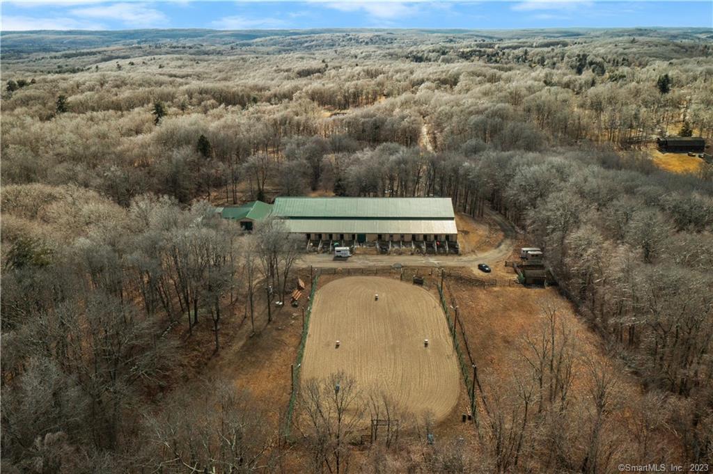 Working horse farm with an indoor arena! Nestled in the Litchfield Hills of Connecticut up a private drive you will find Lazy-D Ranch a full-service horse boarding facility. With 2 barns, 32 stalls, and an indoor and outdoor riding arena this property offers you the opportunity to make your passion for horses and an income-producing lifestyle. The 78x200 indoor riding ring boasting a new roof, 16 attached stalls with runouts, a bathroom, and a heated classroom is the perfect place to host a variety of events from riding lessons to clinics! Just steps away from the main barn you will find a second barn with 16 additional stalls and access to turnout. A short walk from the barns is a 100x200 outdoor riding arena where you can enjoy the fresh air while exercising your horse. With its own private drive and a front porch with pastoral views, the 3 bedroom 2.5 bath cape-style home is the perfect place to unwind after a long day at the barn. The cozy kitchen with solid wood cabinets leads to a dining room open to a large living room complete with a stone fireplace. The first-floor primary bedroom has access to the sweetest sitting room overlooking the front pasture. An additional living room gives you flexibility for office space, a playroom, or a formal living area. Upstairs 2 large bedrooms offer you the opportunity to create a second-level primary bedroom. With so much to offer at an affordable price, you do not want to miss this opportunity to make your equine dreams a reality!