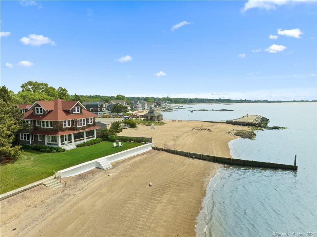 This year-round direct waterfront home called Red Top will captivate you the moment you see it! This historic and charming home was once the residence of the official greeter of New York & President of the World's Fair, Grover Whalen. Whalen, who was known as Mr. New York often hosted prominent people, including Mayor Fiorella LaGuardia and General Douglas MacArthur. When you enter the home, the open floorplan on the main floor offers panoramic views of Long Island Sound from the living room (with stone fireplace), dining area, and study. The kitchen features an island with seating plus a casual dining area great for enjoying meals with family and friends. There's a Subzero refrigerator, two new dishwashers, wine bar, and loads of cabinets and counter space. On the second floor, there's a family room with built-in cabinets and bookshelves, six bedrooms, including three ensuite, all with views of Long Island Sound. The third floor is stunning with vaulted ceilings, a skylight, built-in desks and bookshelves, plus a seventh bedroom with a window seat and full bath.The new patio and spacious 36'x10'6 screened porch was completed in 2022. This professionally landscaped home (with an irrigation system & outdoor shower) is full of lush perennial gardens. The sandy beach is beautiful with a new groin and a substantial sea wall. There's a mooring for your boat too! Make your own special memories at this spectacular beach home in the heart of Middle Beach Road in Madison.