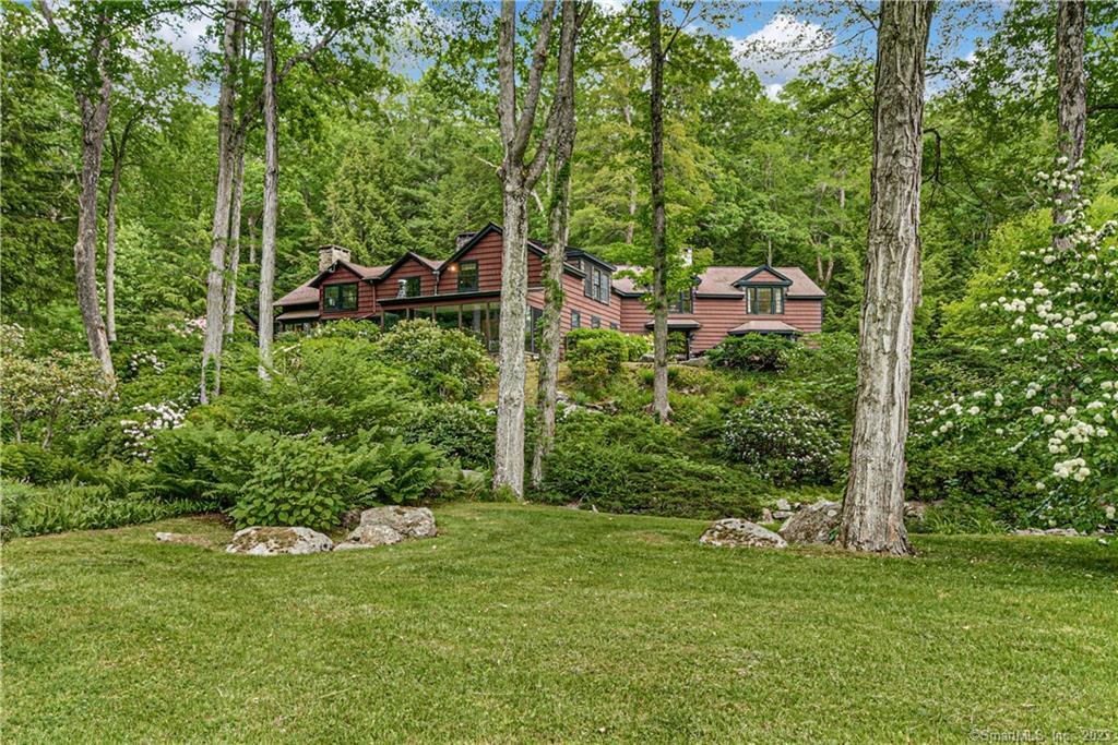 This 1910 wood shingle, Adirondack-style lodge home offers a romantic aura of rustic elegance that is truly a one-of-a-kind lifestyle. A nature lover's paradise and a haven of simple pleasures, warmth and nostalgia, the tranquil retreat is set on 15.9 acres of secluded woods with lush gardens, walking trails, stone paths, a bubbling stream with wooden footbridge, expansive views and inground Gunite pool with stone surround. Showcasing a harmonious blend of natural elements and cozy comforts, the home shines with charming details like massive native stone walls and fireplaces, chunky log beams, tucked-away alcoves and window seats, and airy windows and French doors. The original portion of the home boasts original wide plank wood floors and abundant historic character, while a later addition added modern conveniences like an updated eat-in-kitchen and gracious formal living room. Other stunning spaces include a stately entry foyer, expansive great room/dining room combination, sun room with wood stove and floor-to-ceiling windows, screened-in porch, upper-level office space with dramatic stone archway, and an airy, spacious and refined primary bedroom suite. Property also includes a 2-car detached garage with a guest apartment and a barn with 2 car bays and storage area. Don’t miss the chance to preserve this family retreat for the next generation and a lifetime of memories! Only 65 mi from NYC, and a world away from the hustle and bustle of urban life. An uncommon treasure.